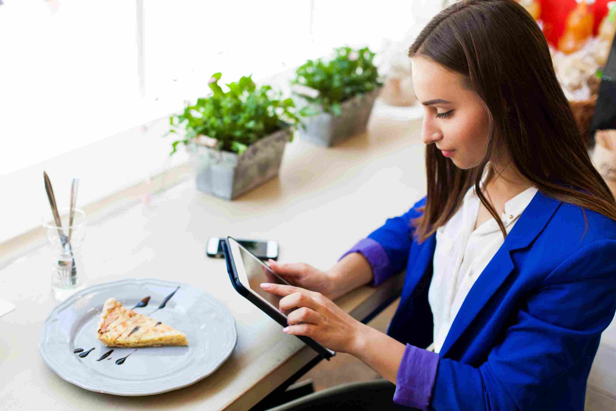 Woman in blue blazer looking at a tablet in a restaurant setting
