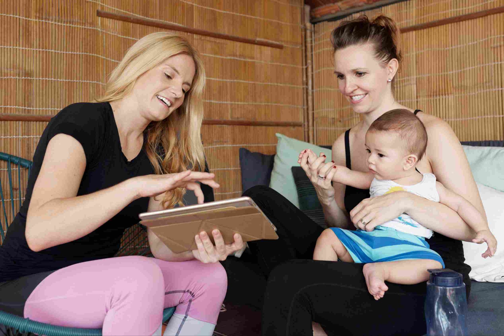 Two women with a baby, one holding a tablet