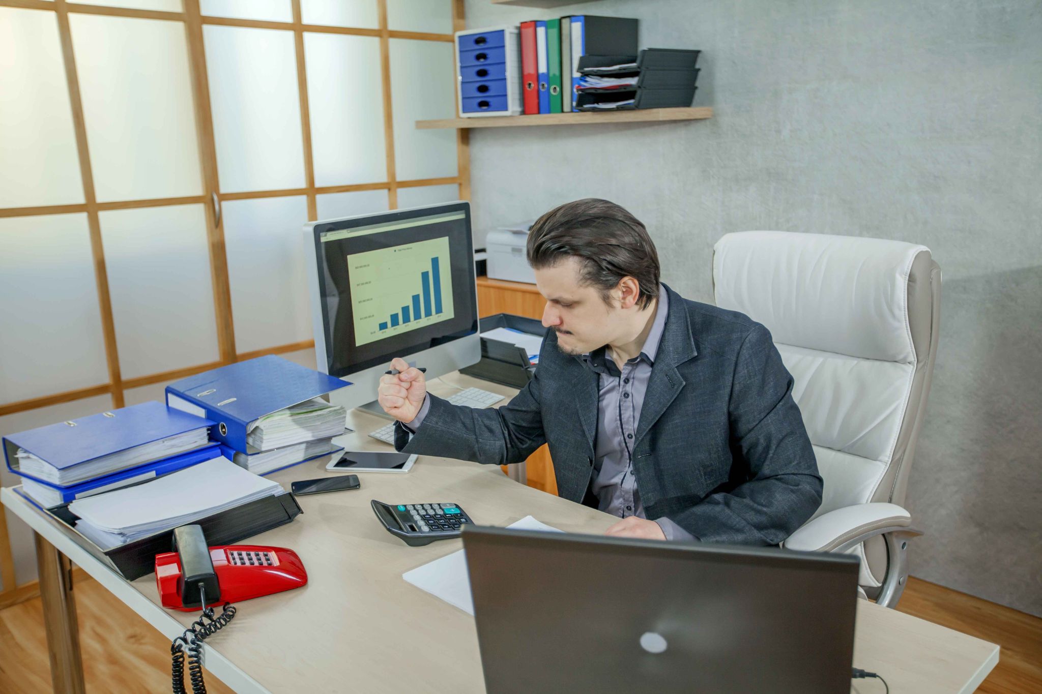 Business manager reviewing financial reports and payroll data in an office