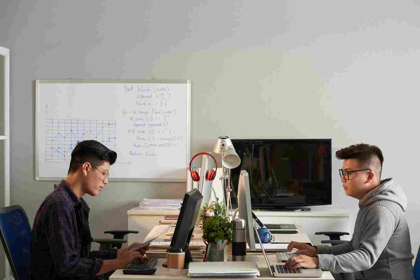 Two male employees working at their computers in an office