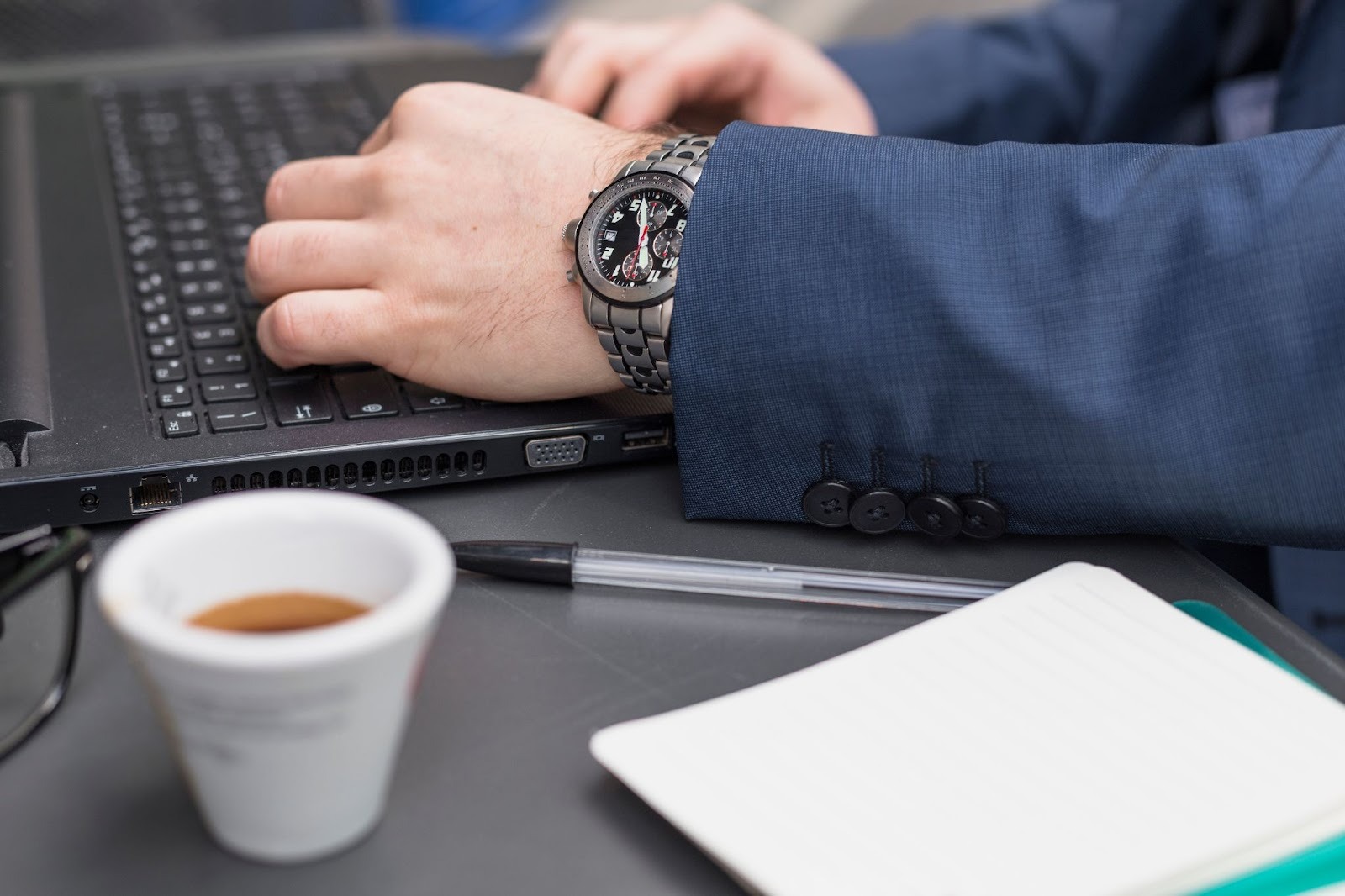 Person's hands on a laptop with a coffee cup nearby
