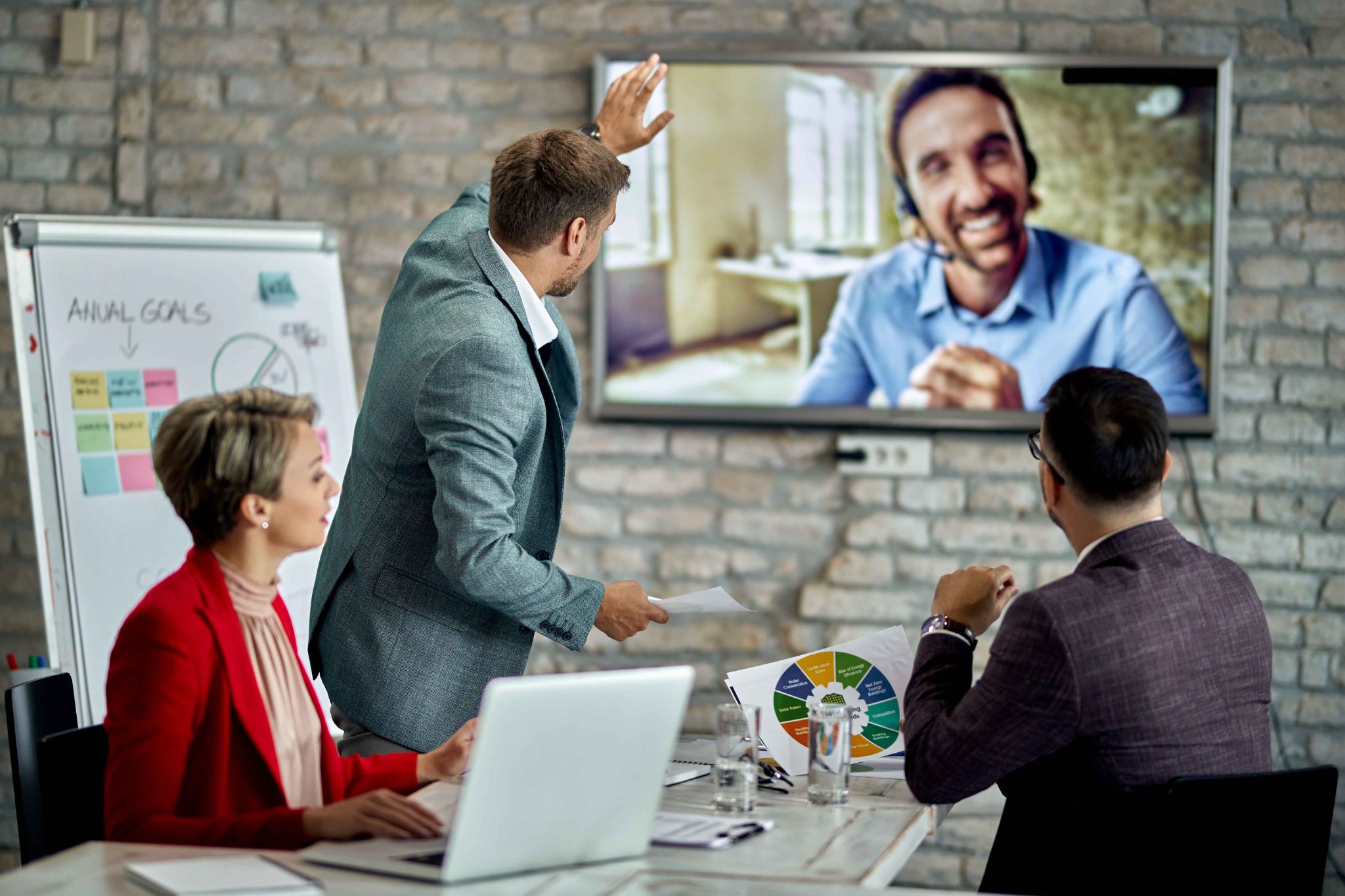 Business team in a hybrid meeting with a remote colleague on screen