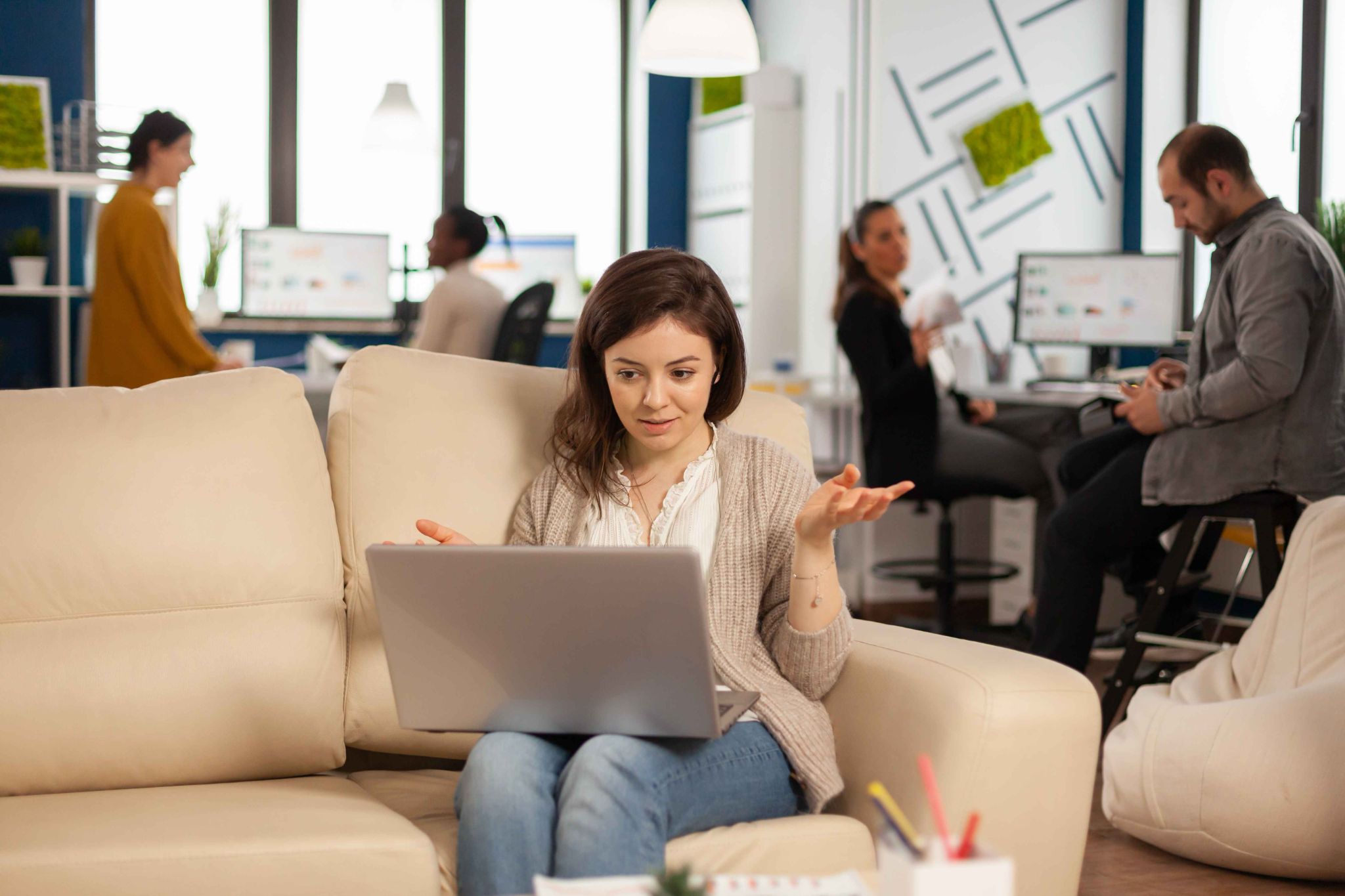 Remote worker using laptop while team works in the background