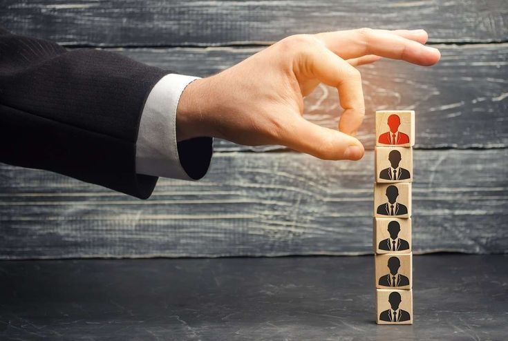 Hand stacking wooden blocks with people icons representing management structure