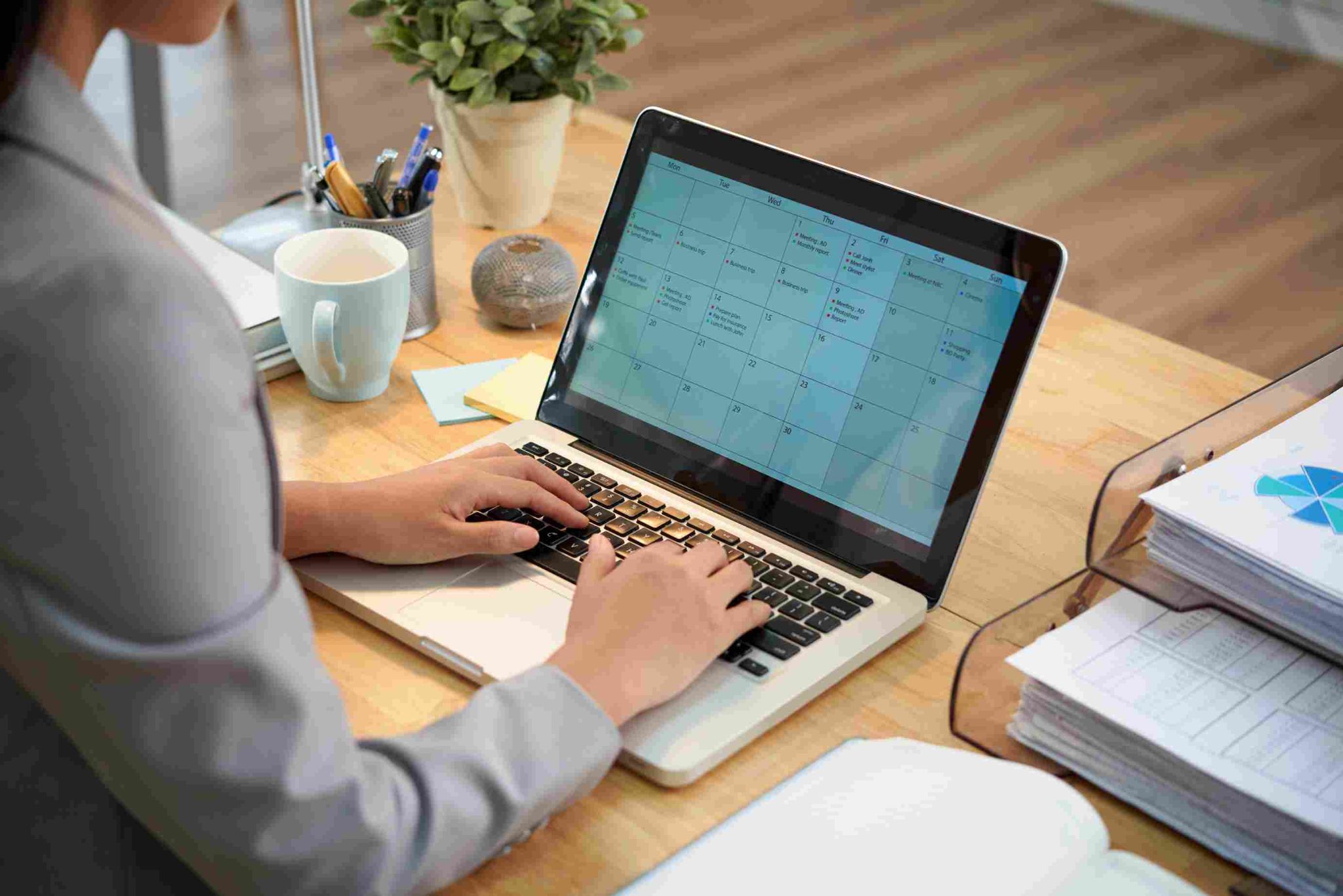 Person typing on a laptop with a calendar on screen
