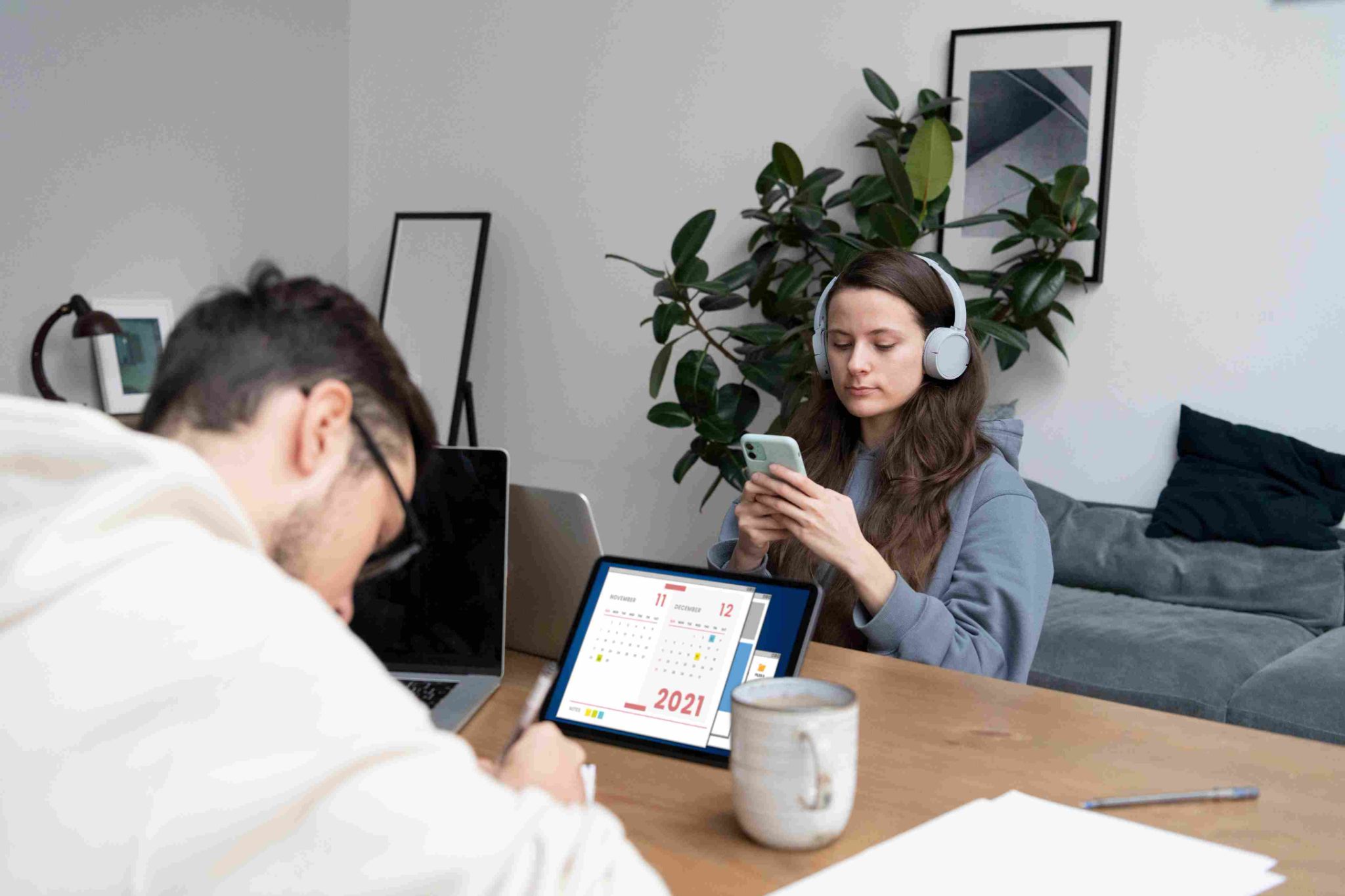 Two people working at a desk, one using a tablet