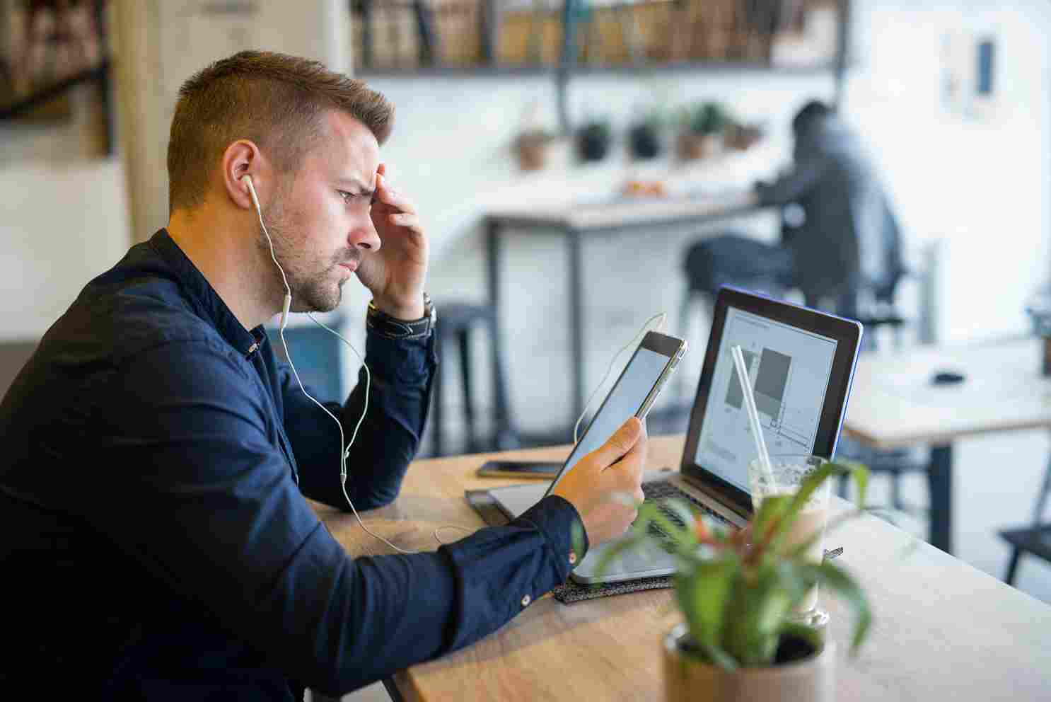 Man looking stressed while using a tablet or smartphone at his desk
