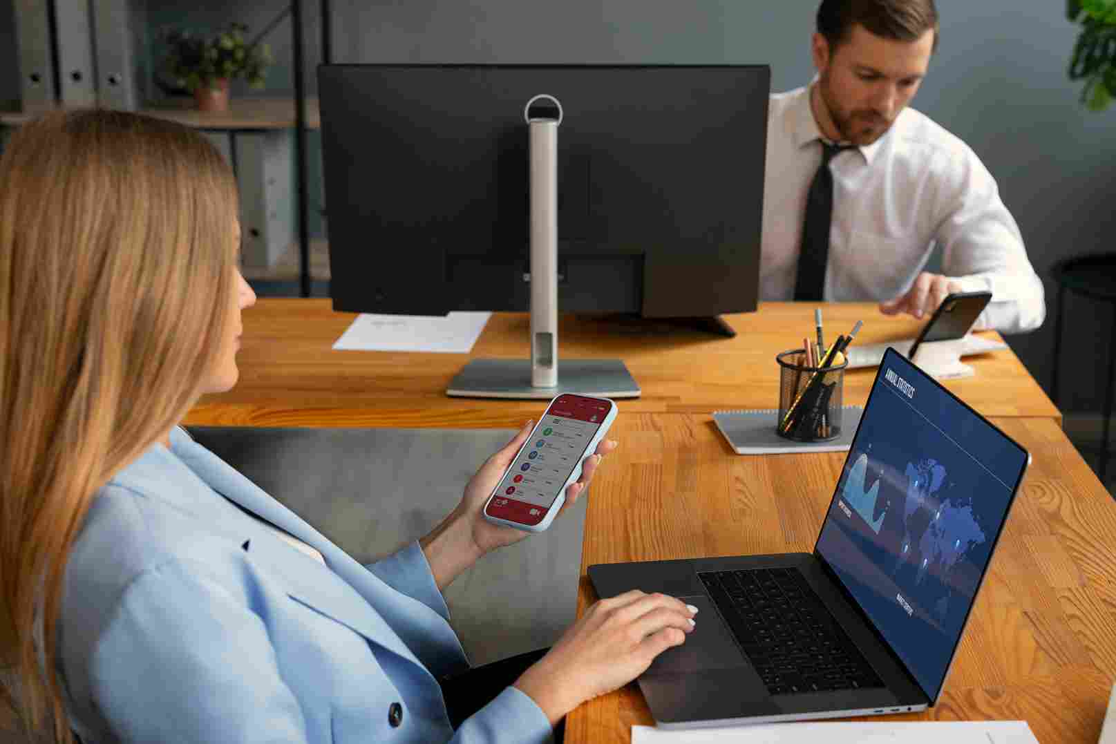 Colleagues working in an office, one using a smartphone