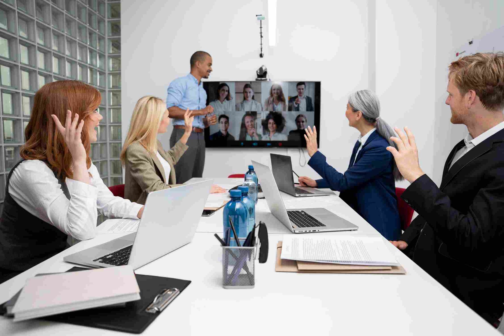 A group of business people in a meeting room raising their hands