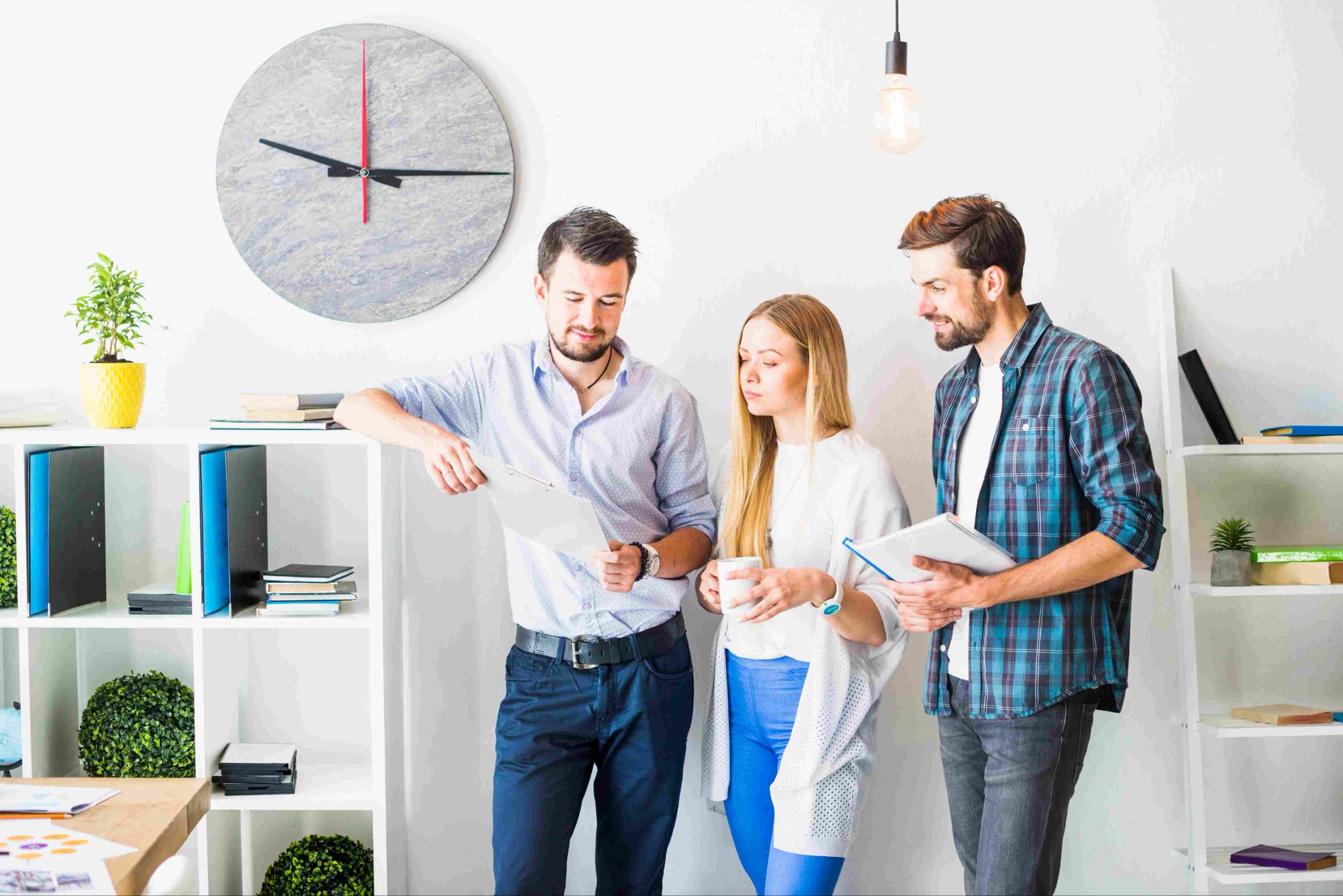 Three colleagues in an office discussing work on a tablet