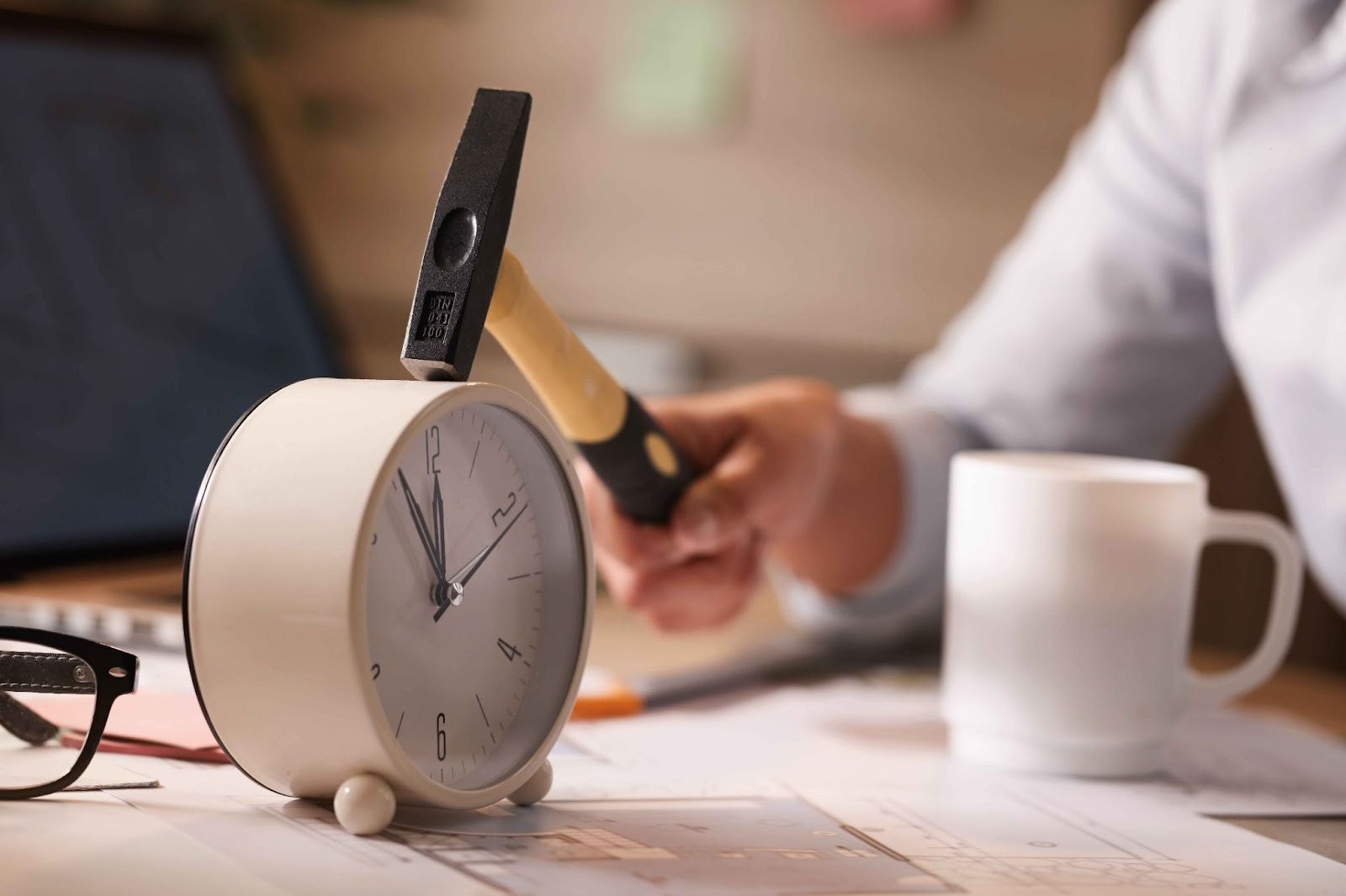 Hand holding a hammer over an alarm clock