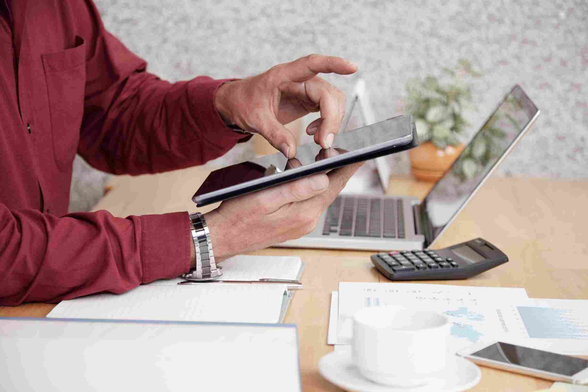 Person using a tablet and calculator on a desk