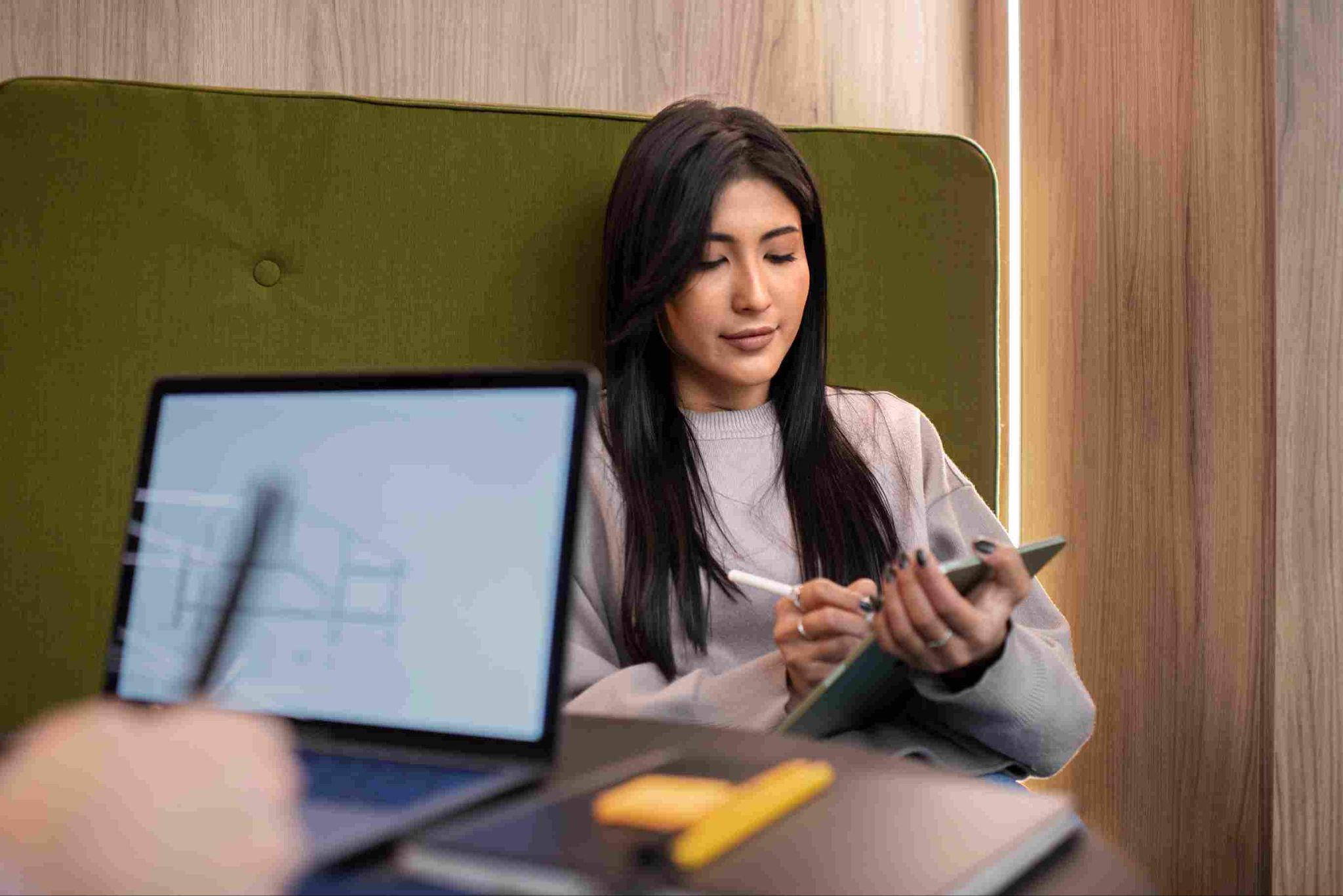 Woman sitting at a desk looking at a laptop and holding a pen