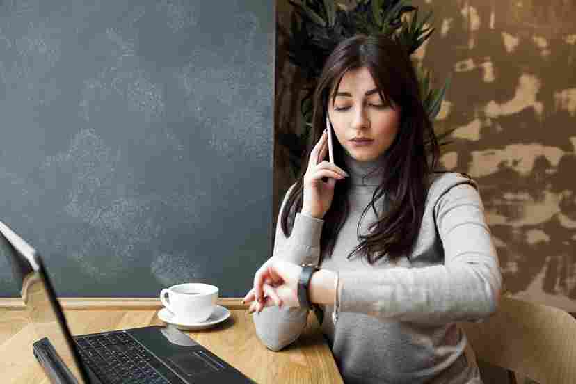 Woman talking on her phone while looking at a laptop