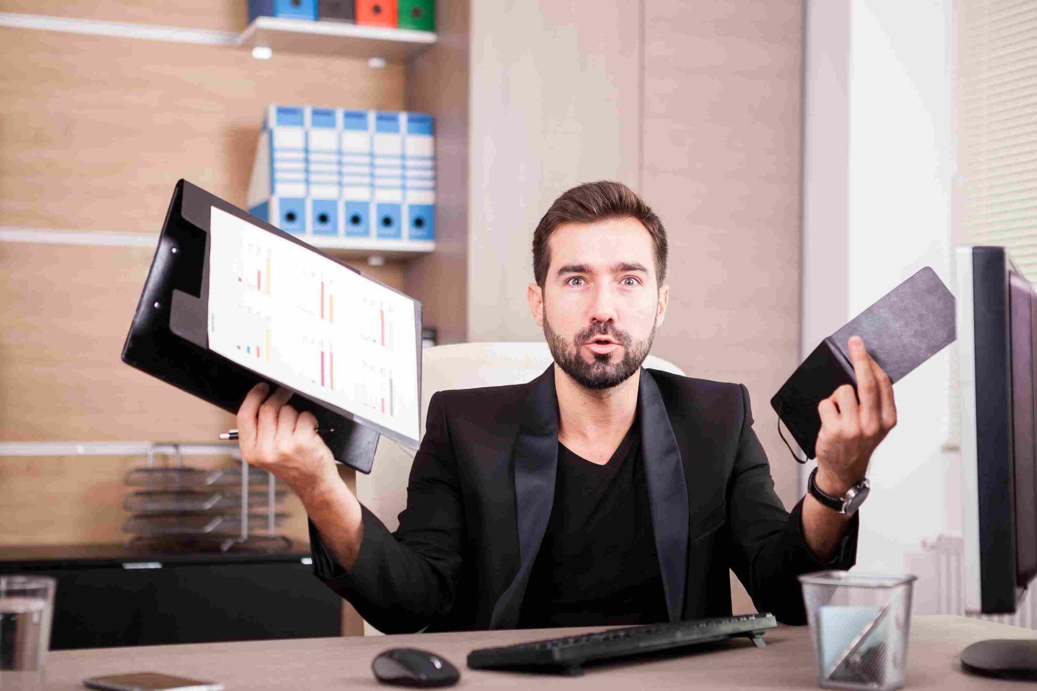 Stressed man in suit holding papers and tablet