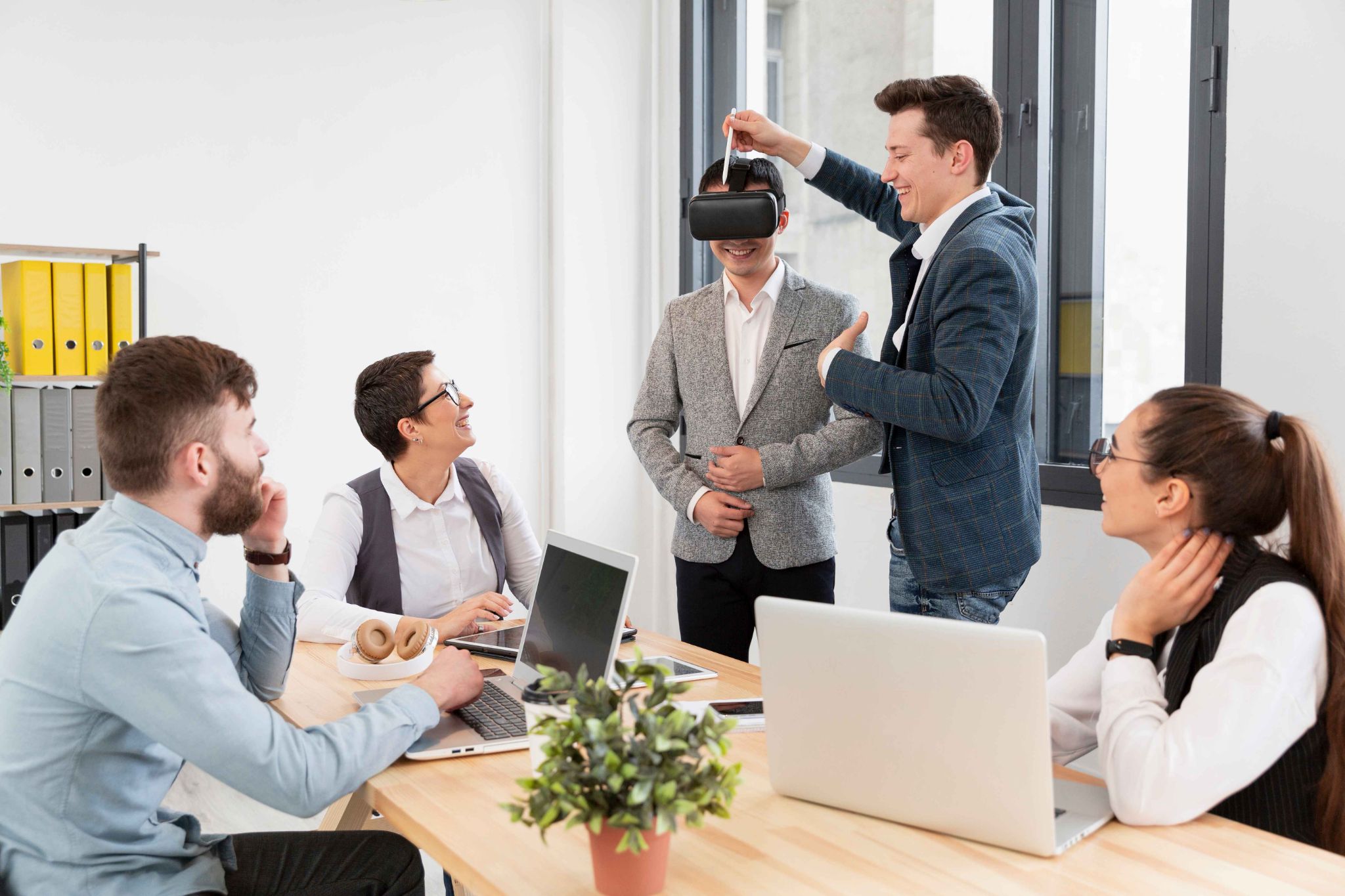 Team members collaborating in an office while one uses a VR headset