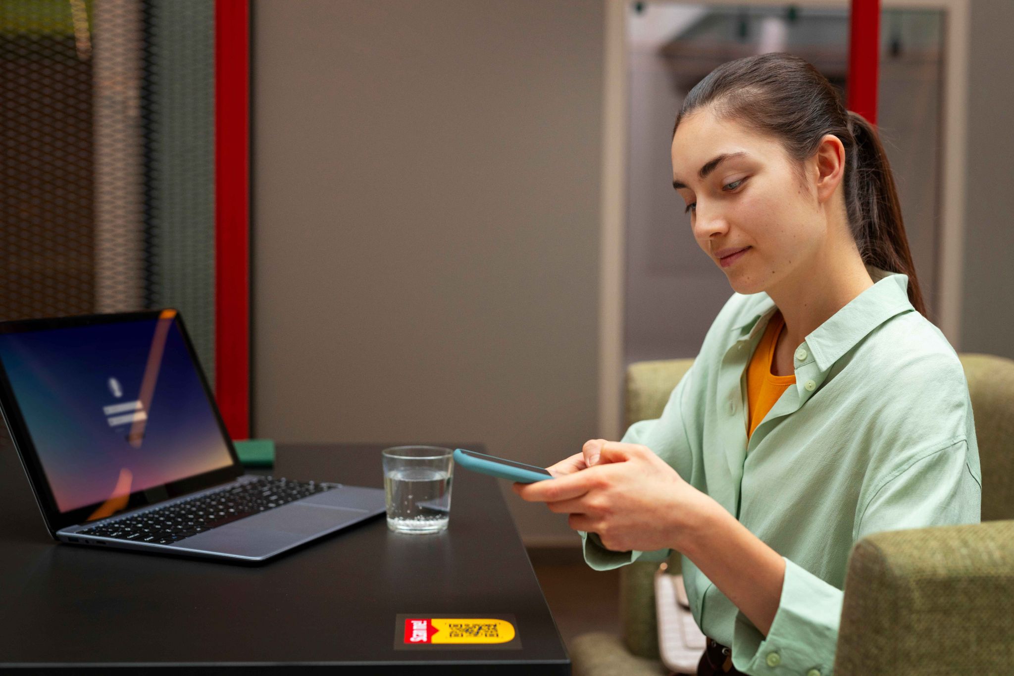 Woman using phone and laptop for payroll processing