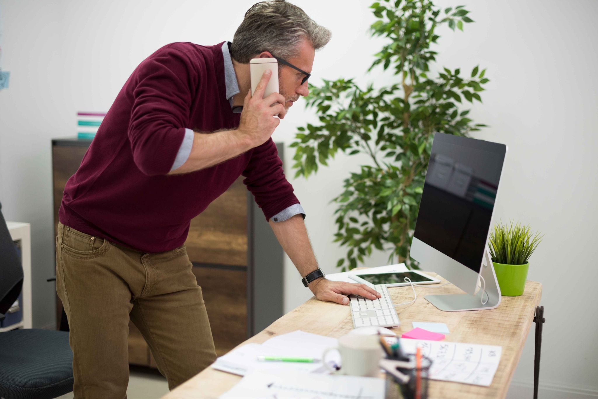 Man looking closely at computer screen, managing schedules