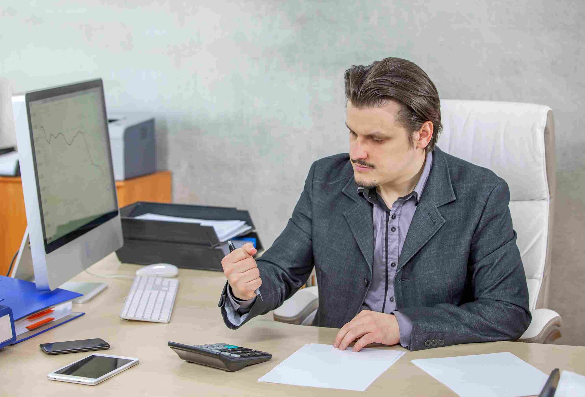 Man in a suit looking at a laptop and pointing