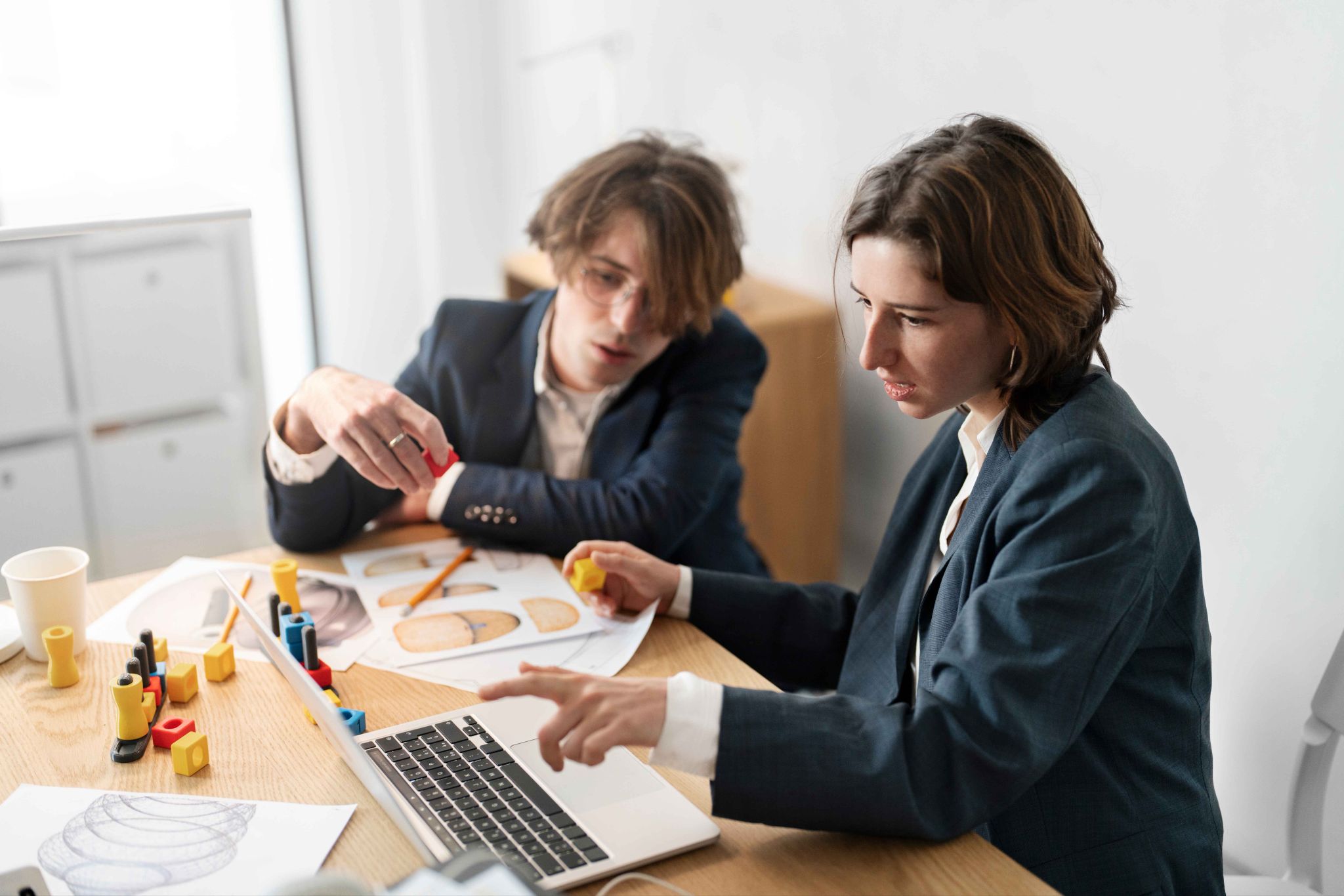 Two people looking at a laptop and design materials