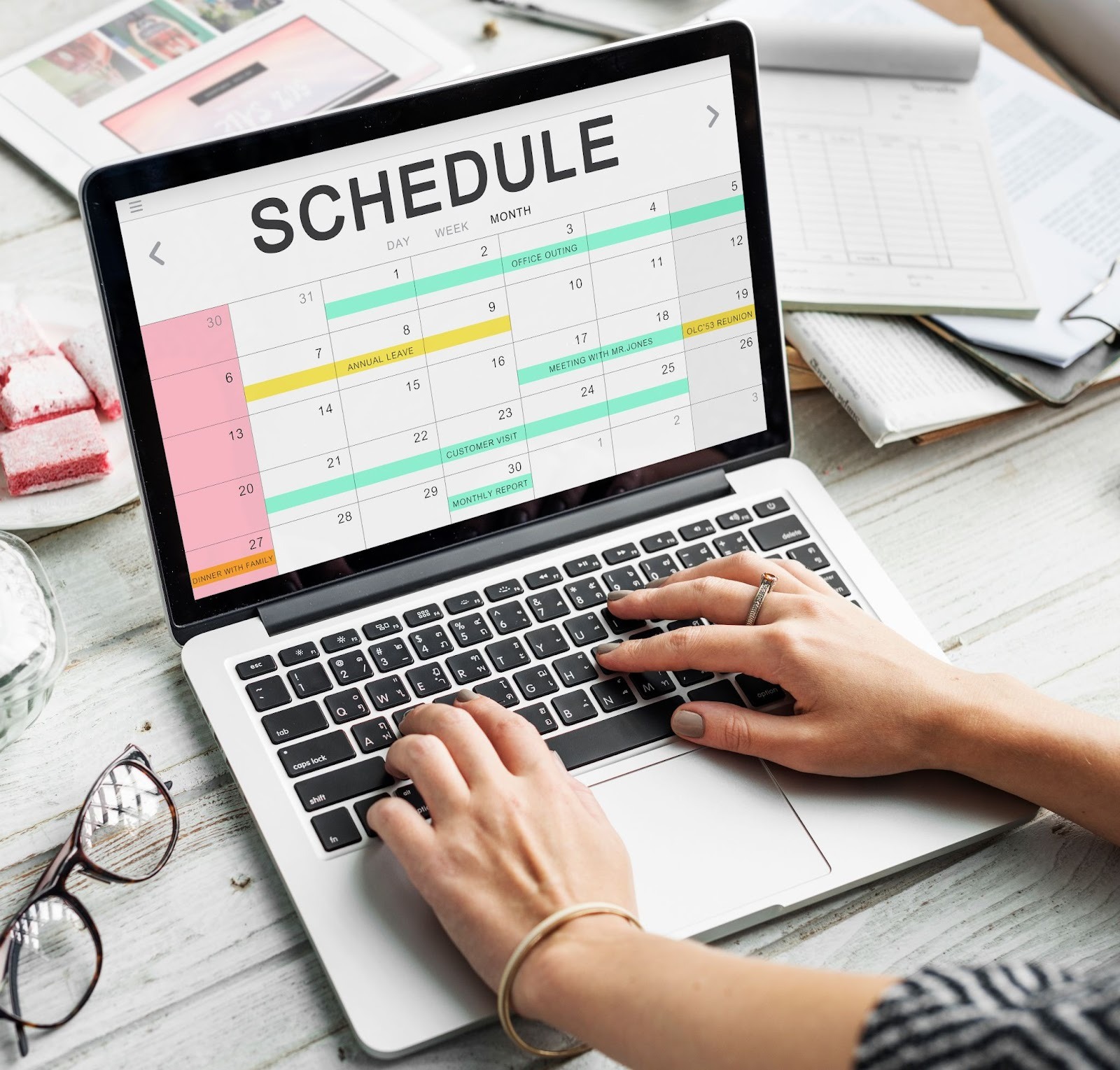 Person typing on a laptop with a SCHEDULE spreadsheet open