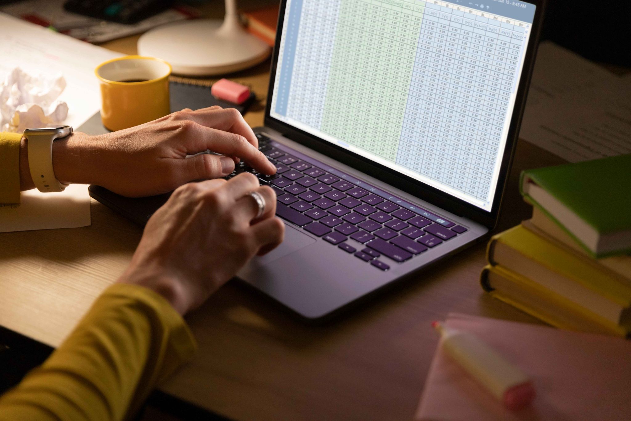 Person comparing spreadsheet data on a laptop