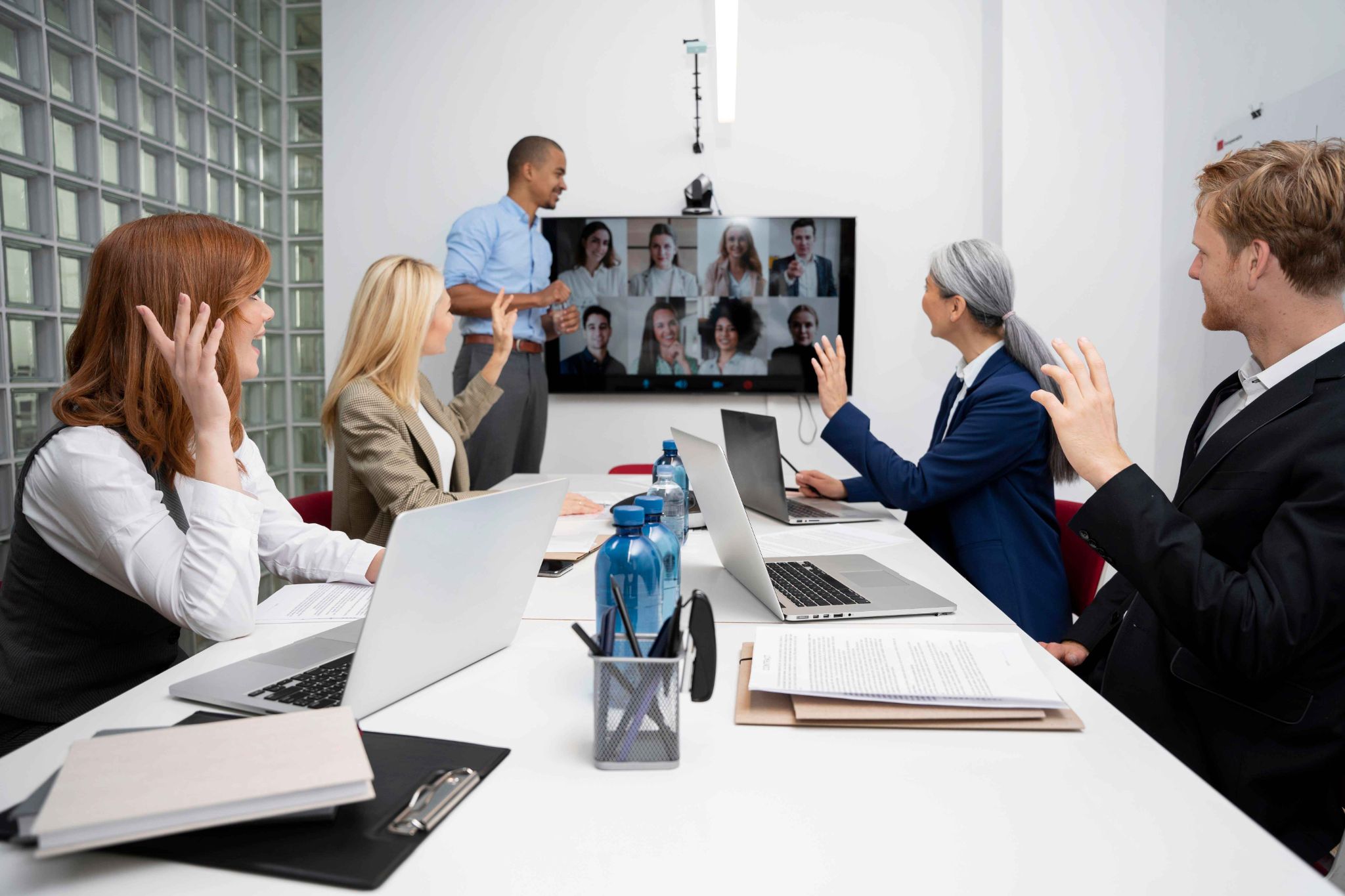 Hybrid team meeting with members raising hands