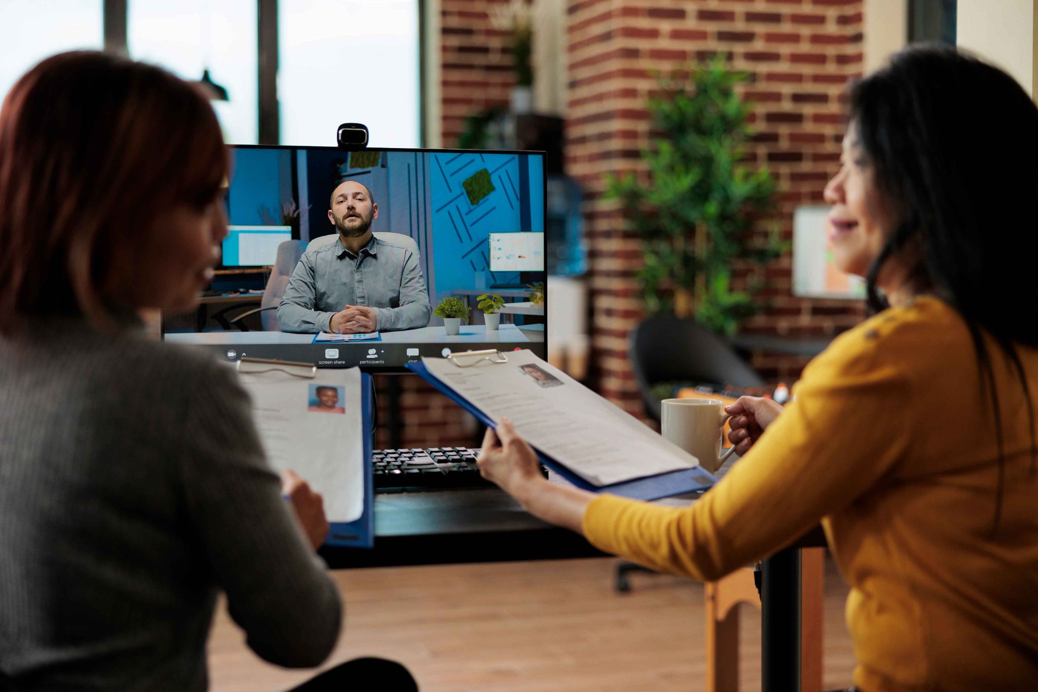 Two women looking at a screen collaborating with a remote worker
