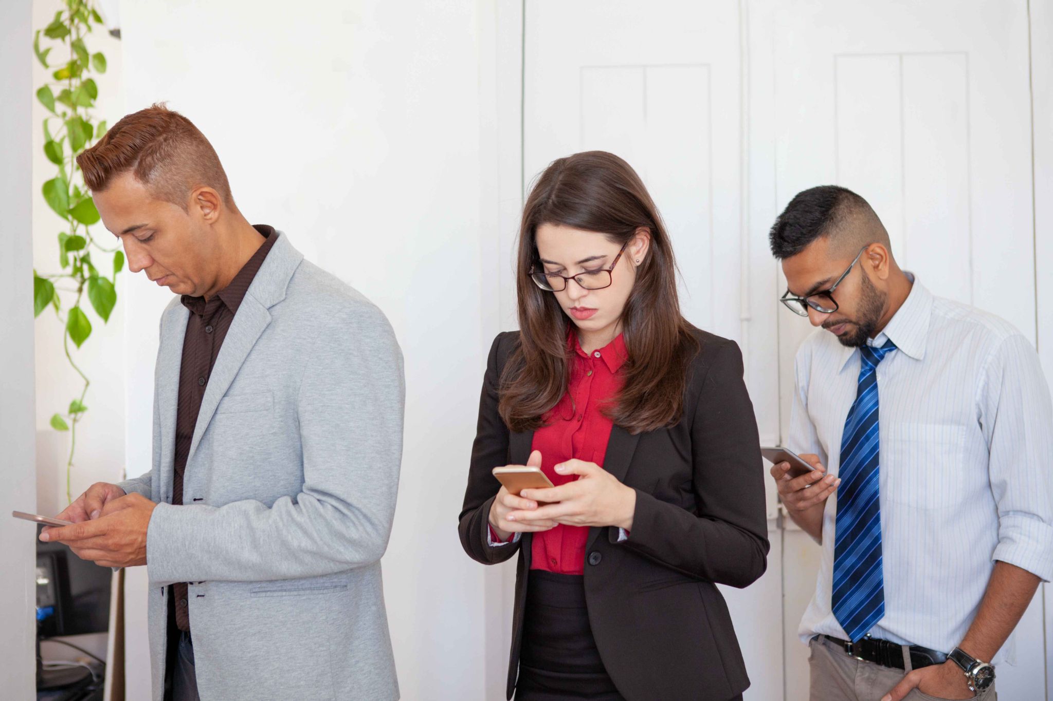 Three employees looking at their smartphones