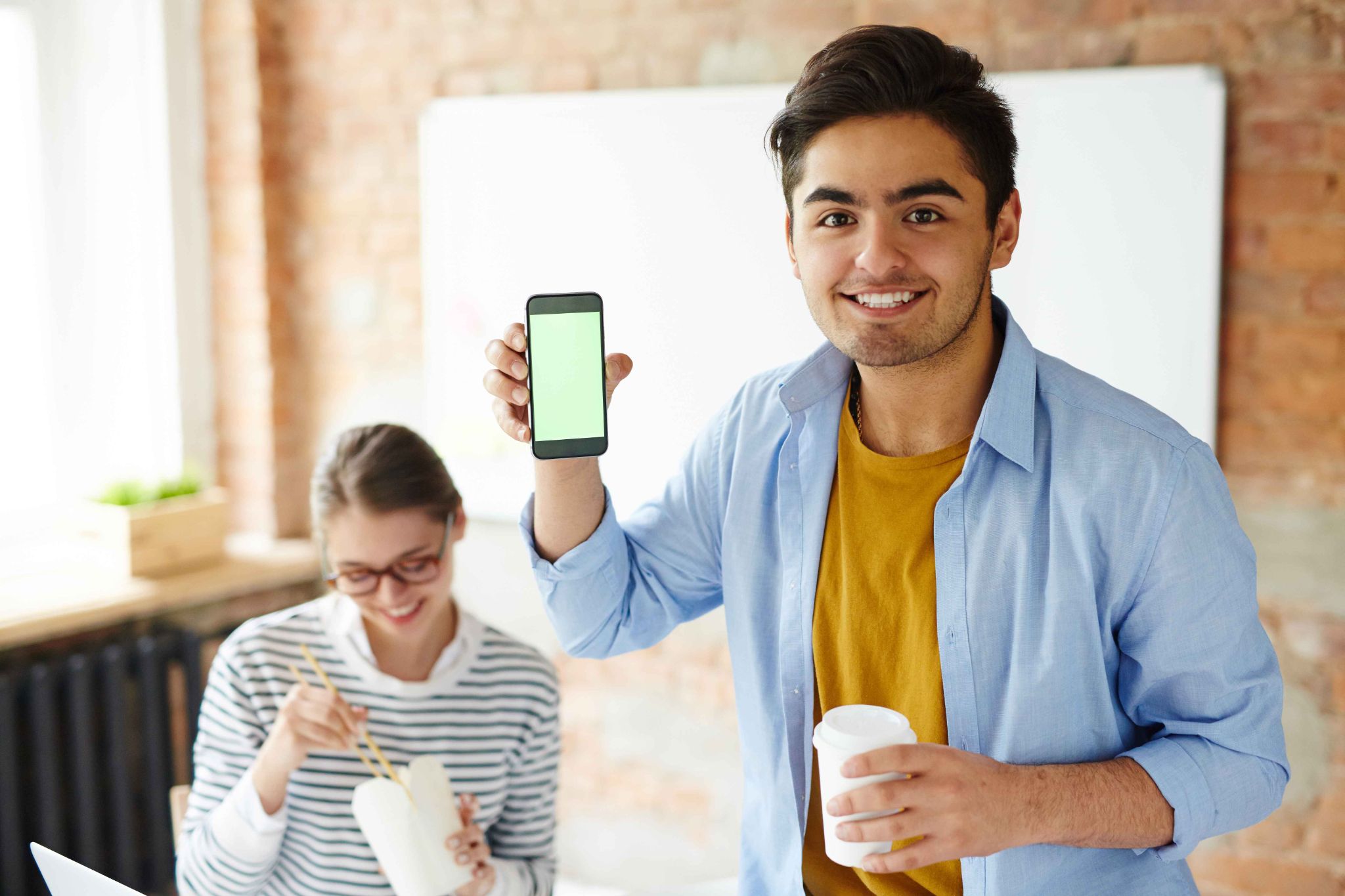 Man holding up a phone with a green screen