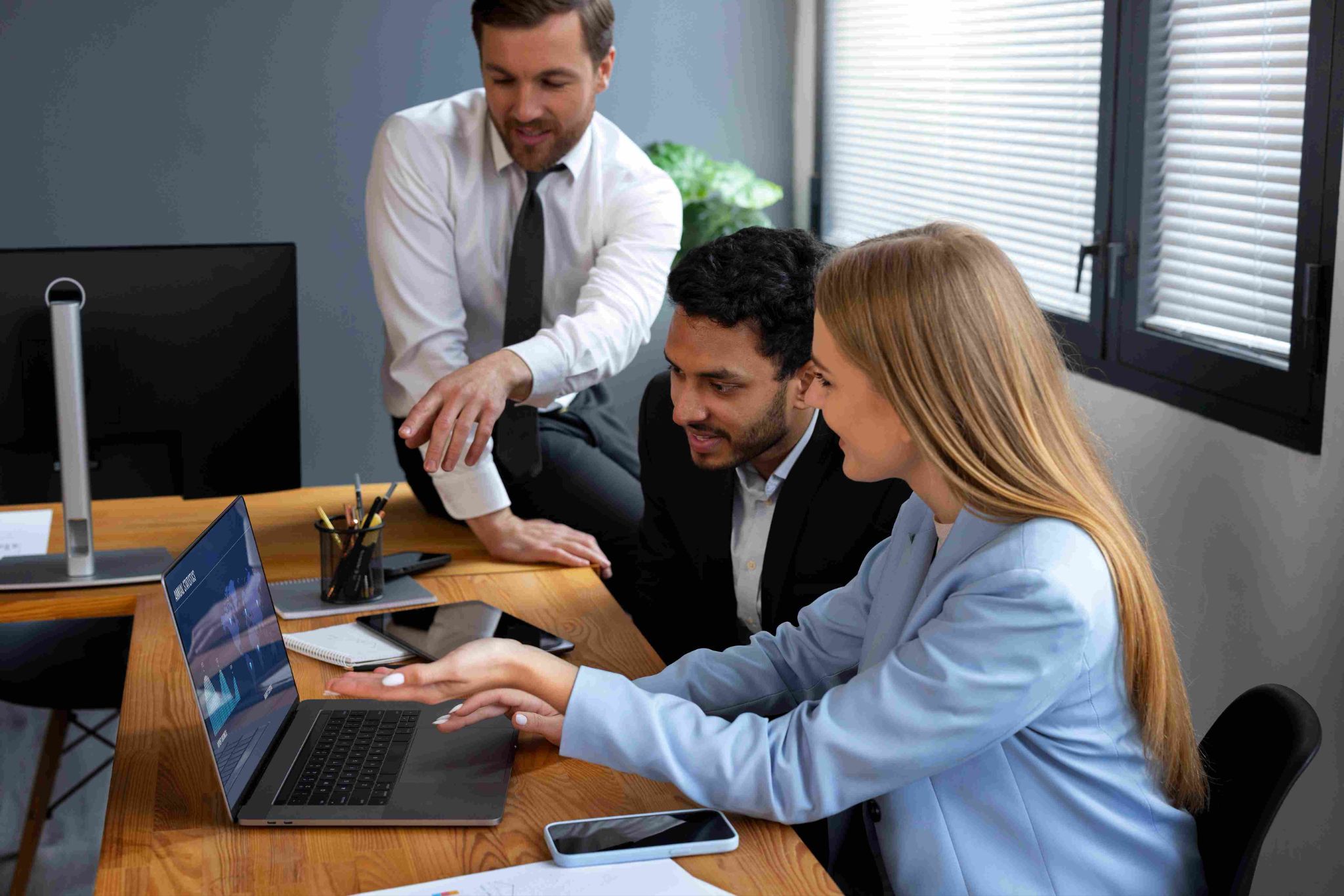 Three people looking at a laptop, one standing and pointing