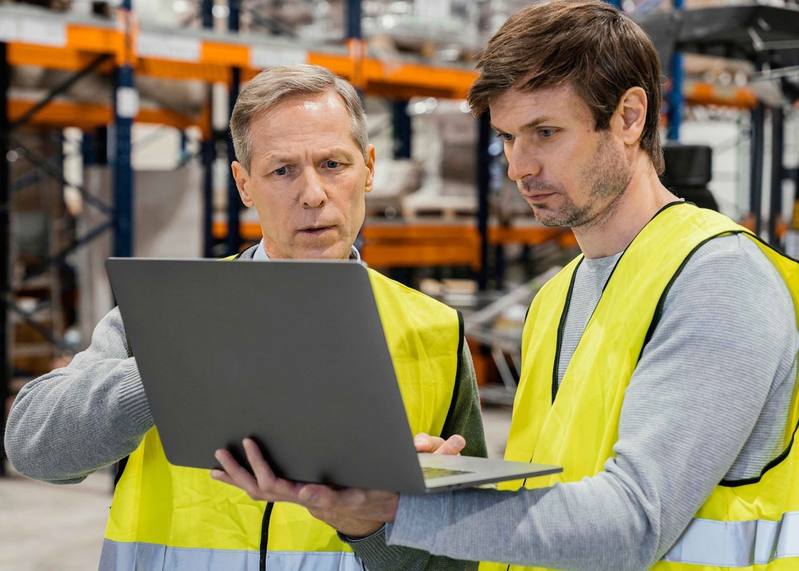 Two manufacturing supervisors reviewing data on a laptop