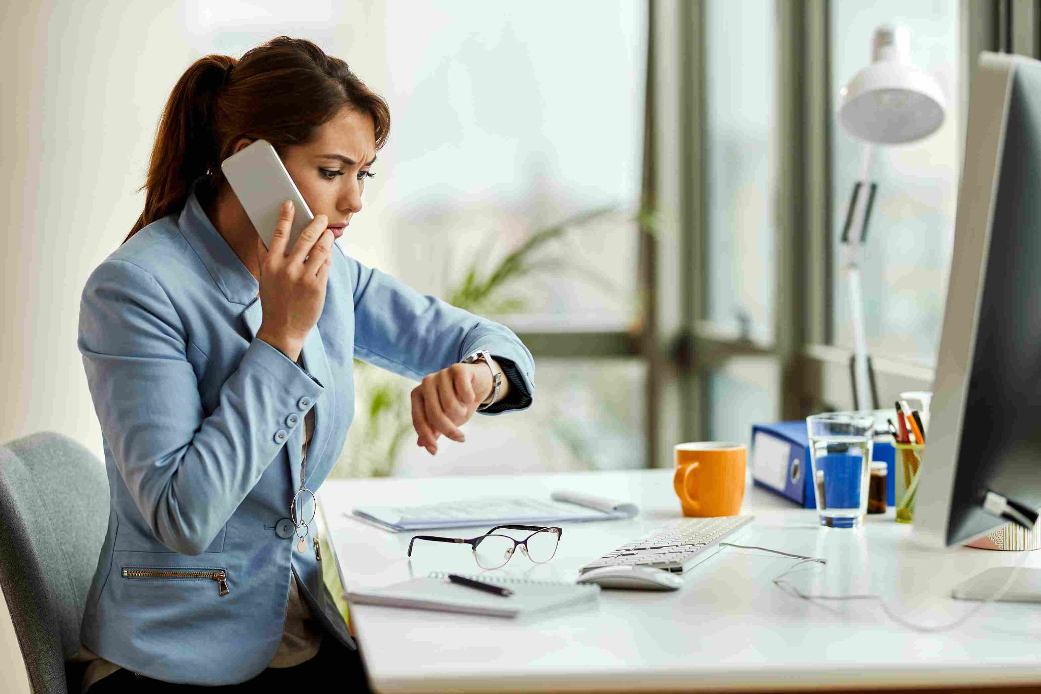 Woman looking at phone and watch at a desk