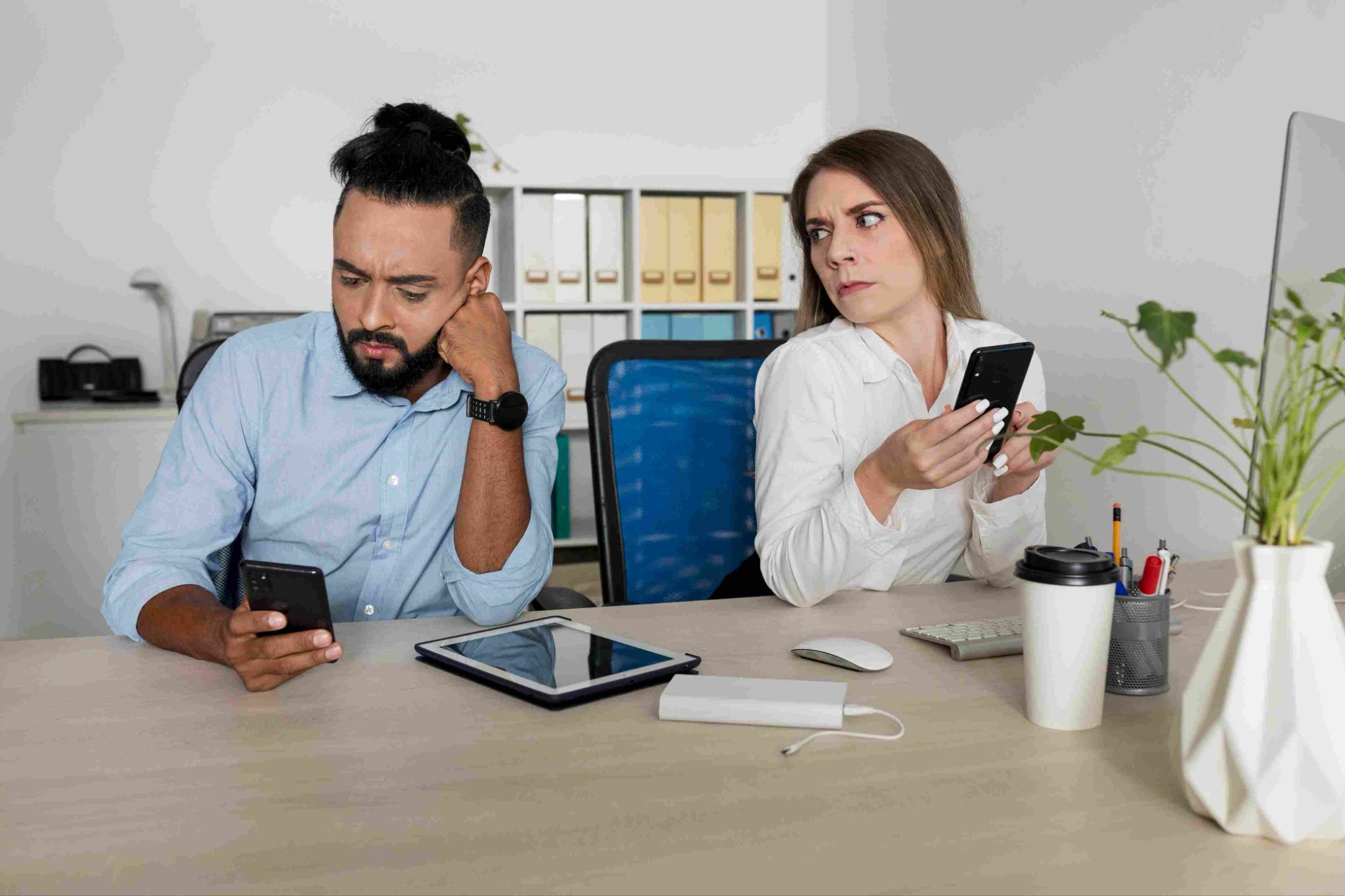 Two people at a desk looking at phones and tablets