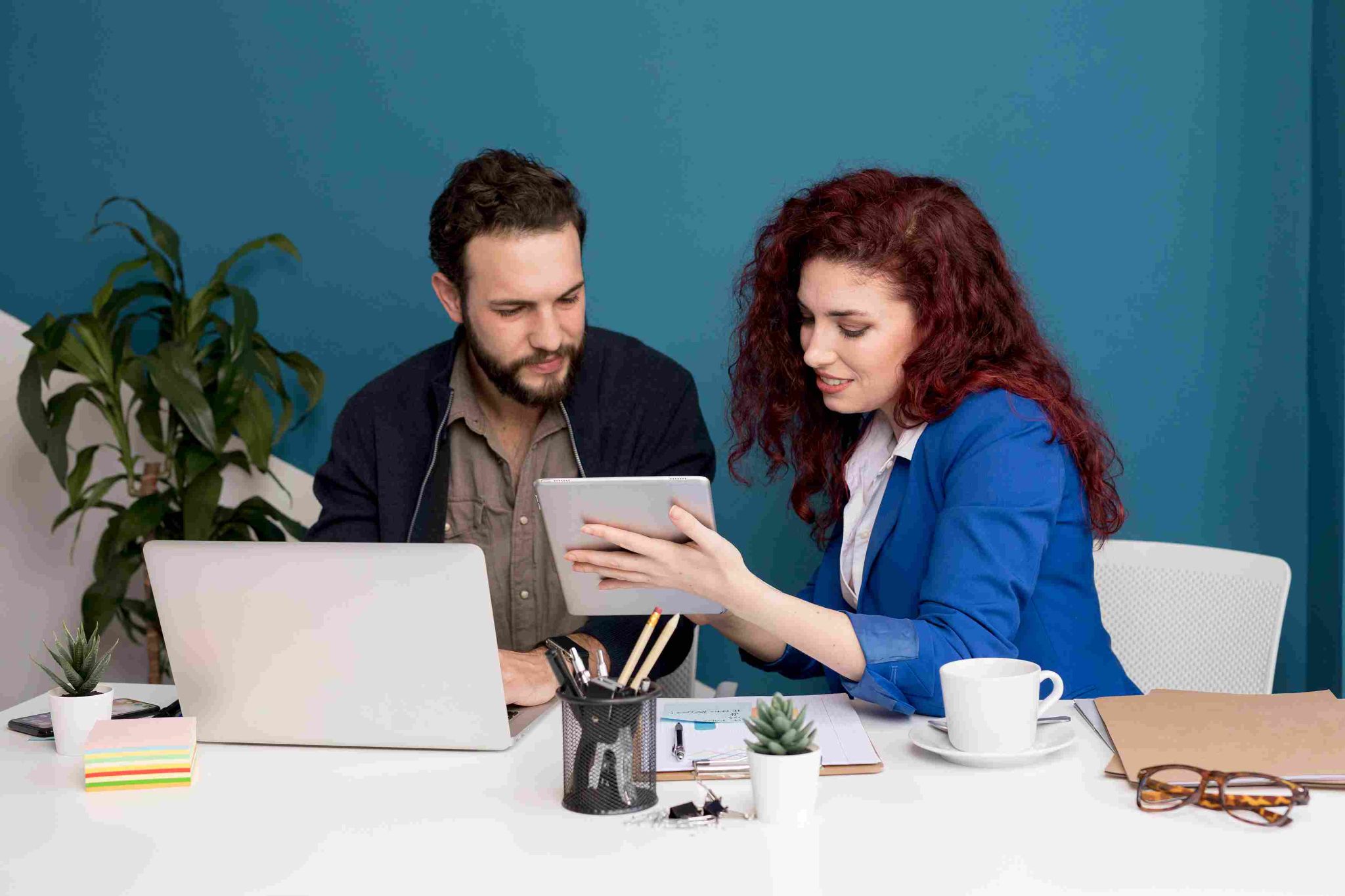 Two people working happily at a desk with laptop and tablet