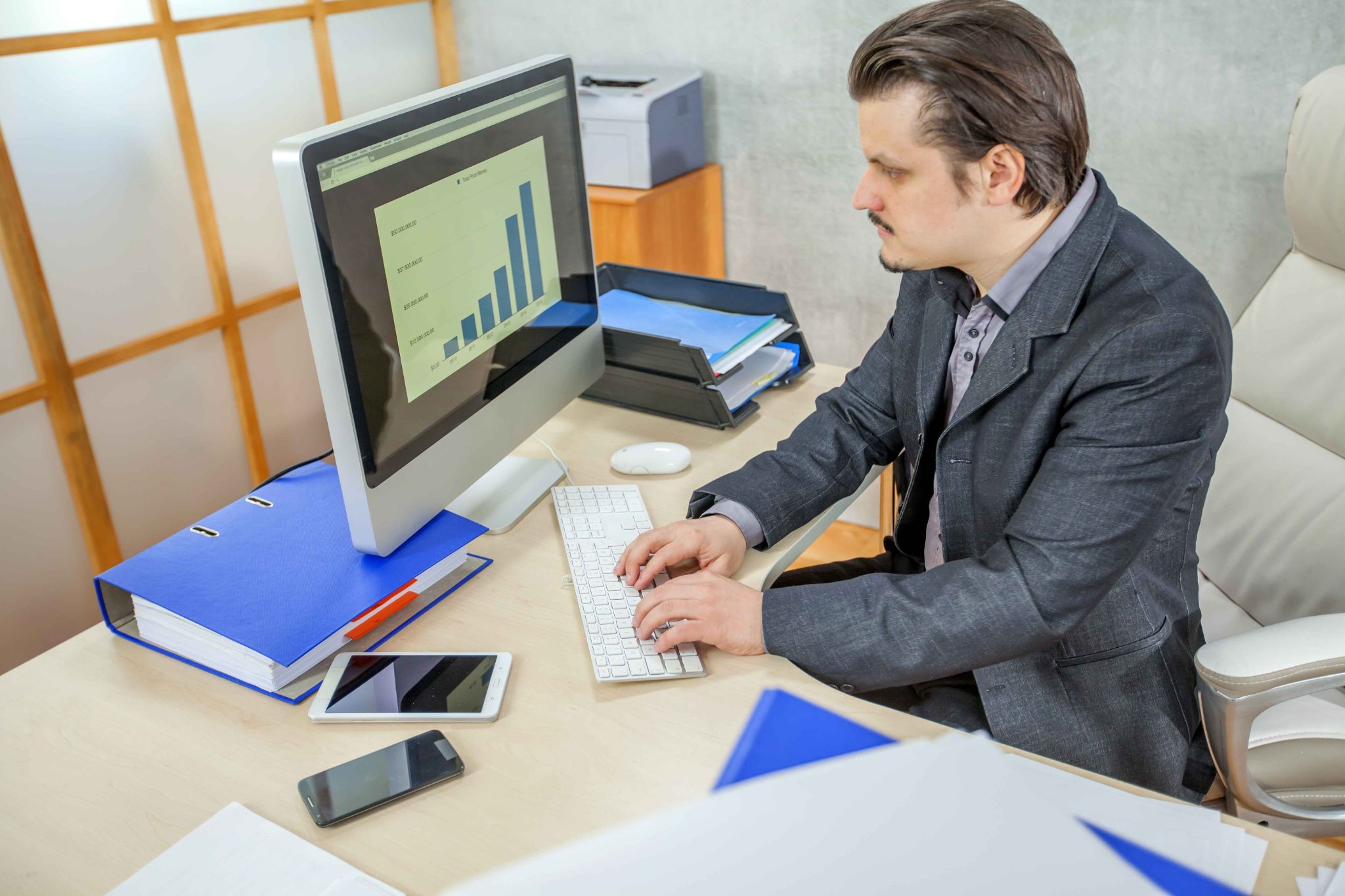Manager using desktop computer with charts for QR code and barcode attendance tracking