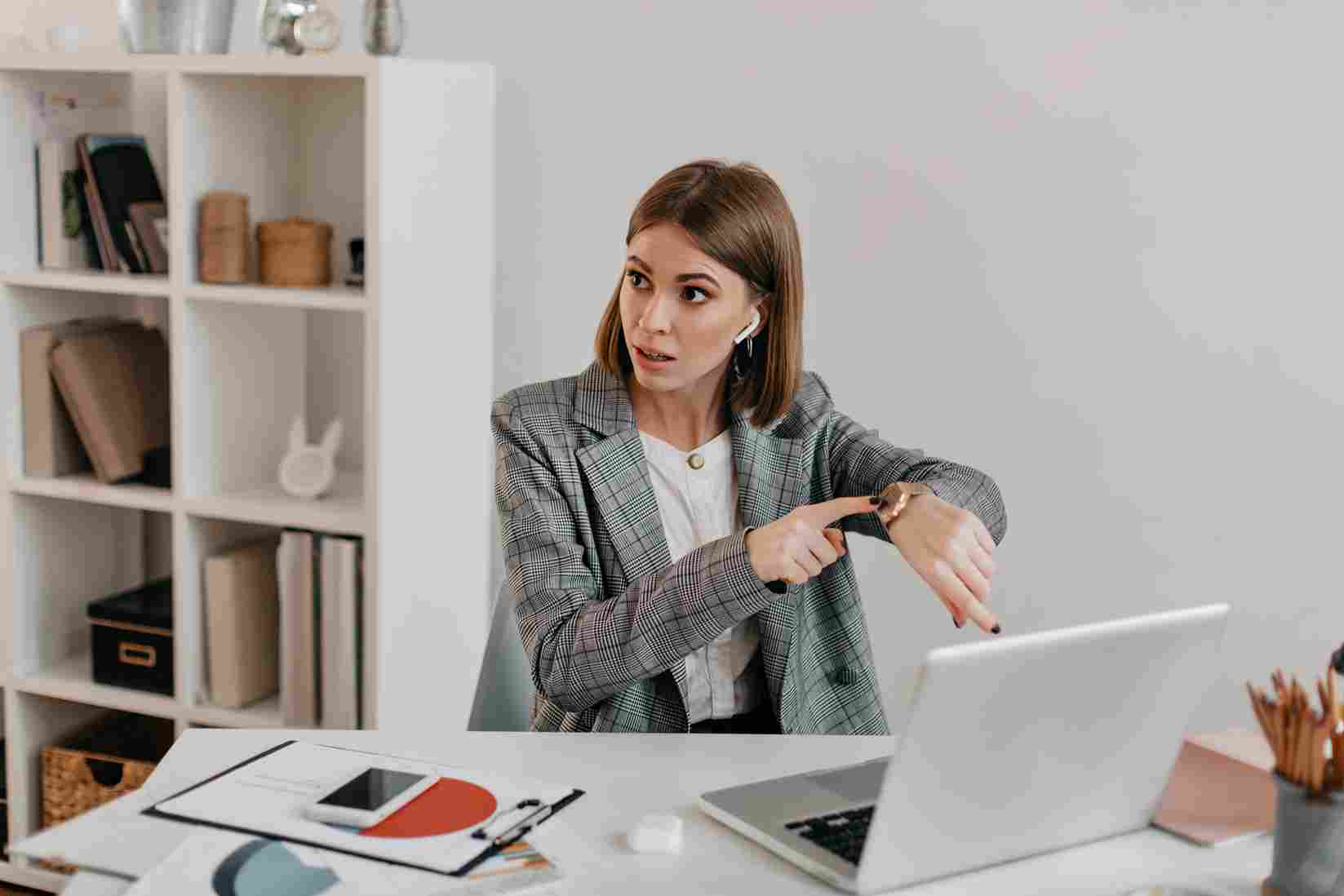 Woman looking at her watch while working at her desk