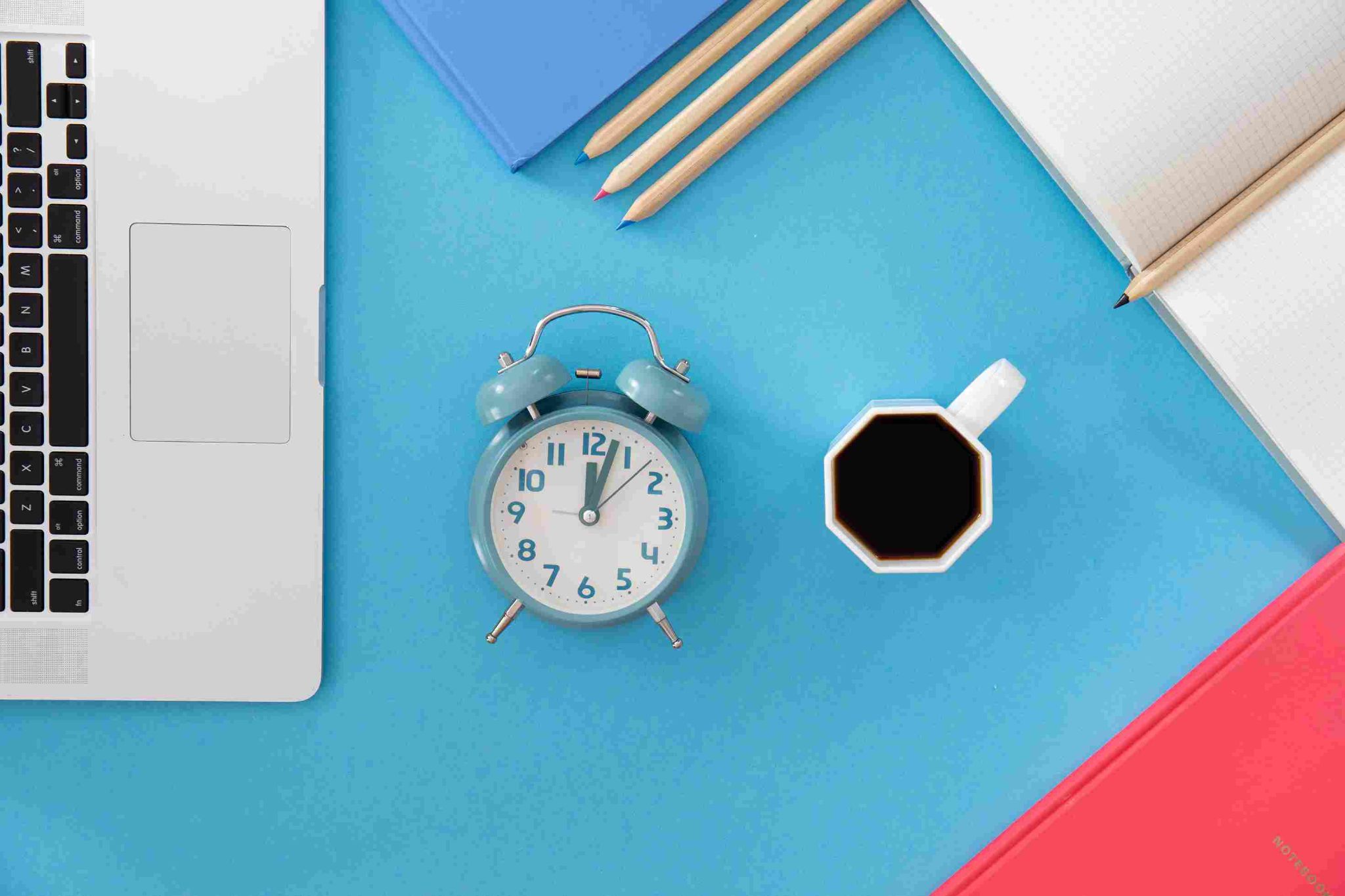 Alarm clock, coffee, laptop, and plant on a desk