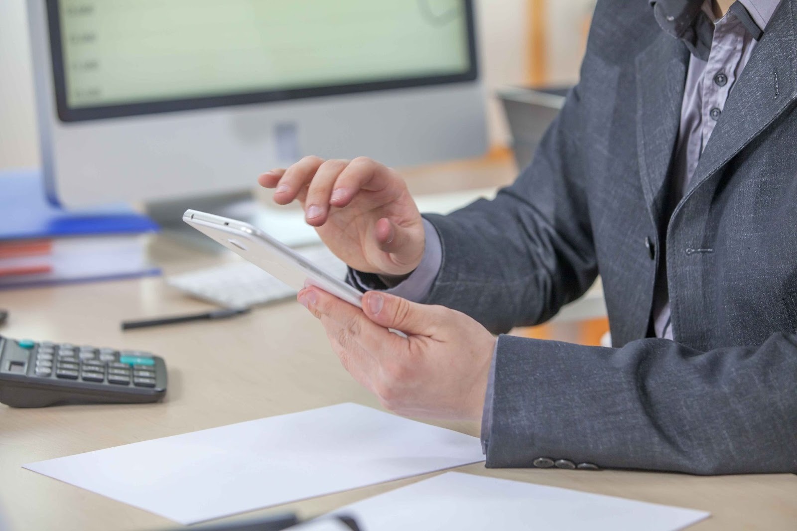 Person looking at a tablet with calculator on desk