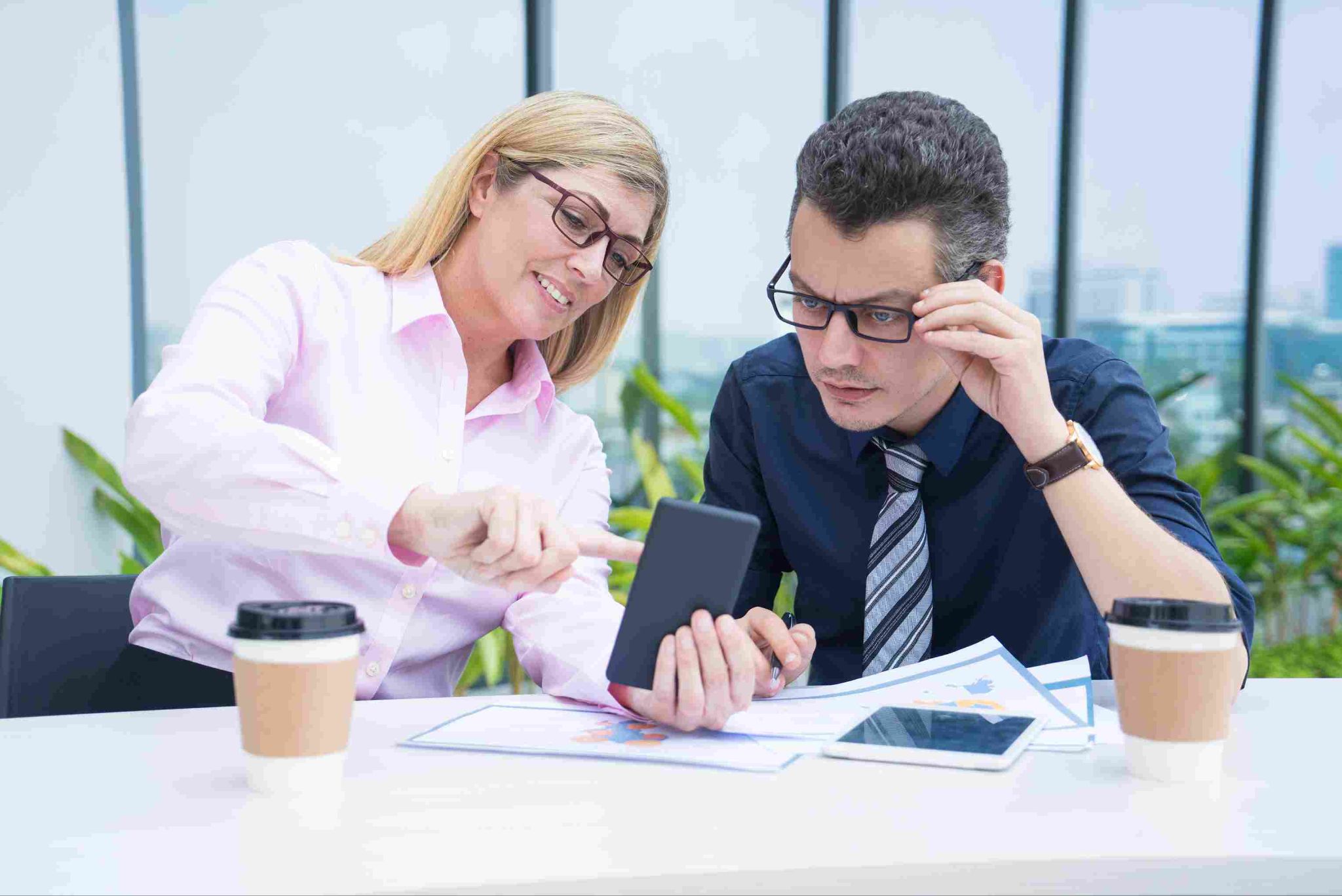 Two people looking at a tablet and discussing payroll records