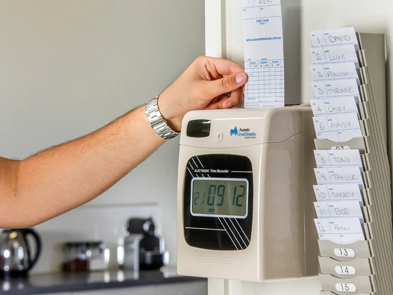 Person inserting a time card into a traditional time clock