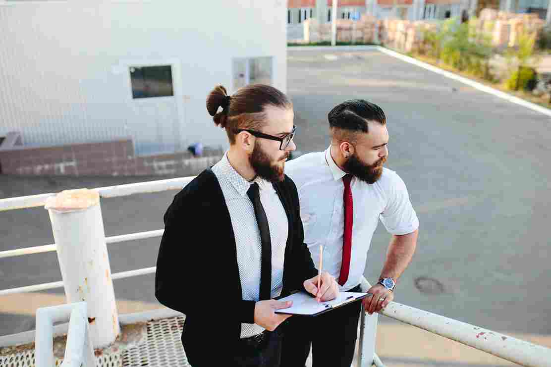 Two men reviewing documents outdoors