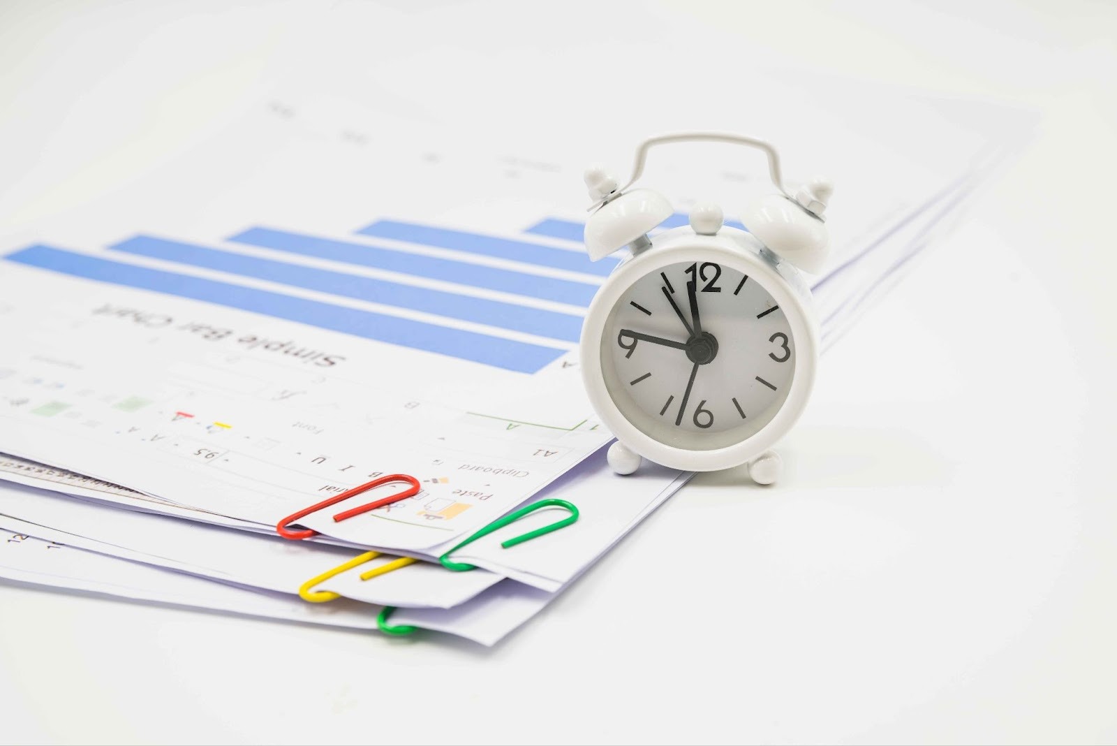 Clock on top of charts and papers with paperclips