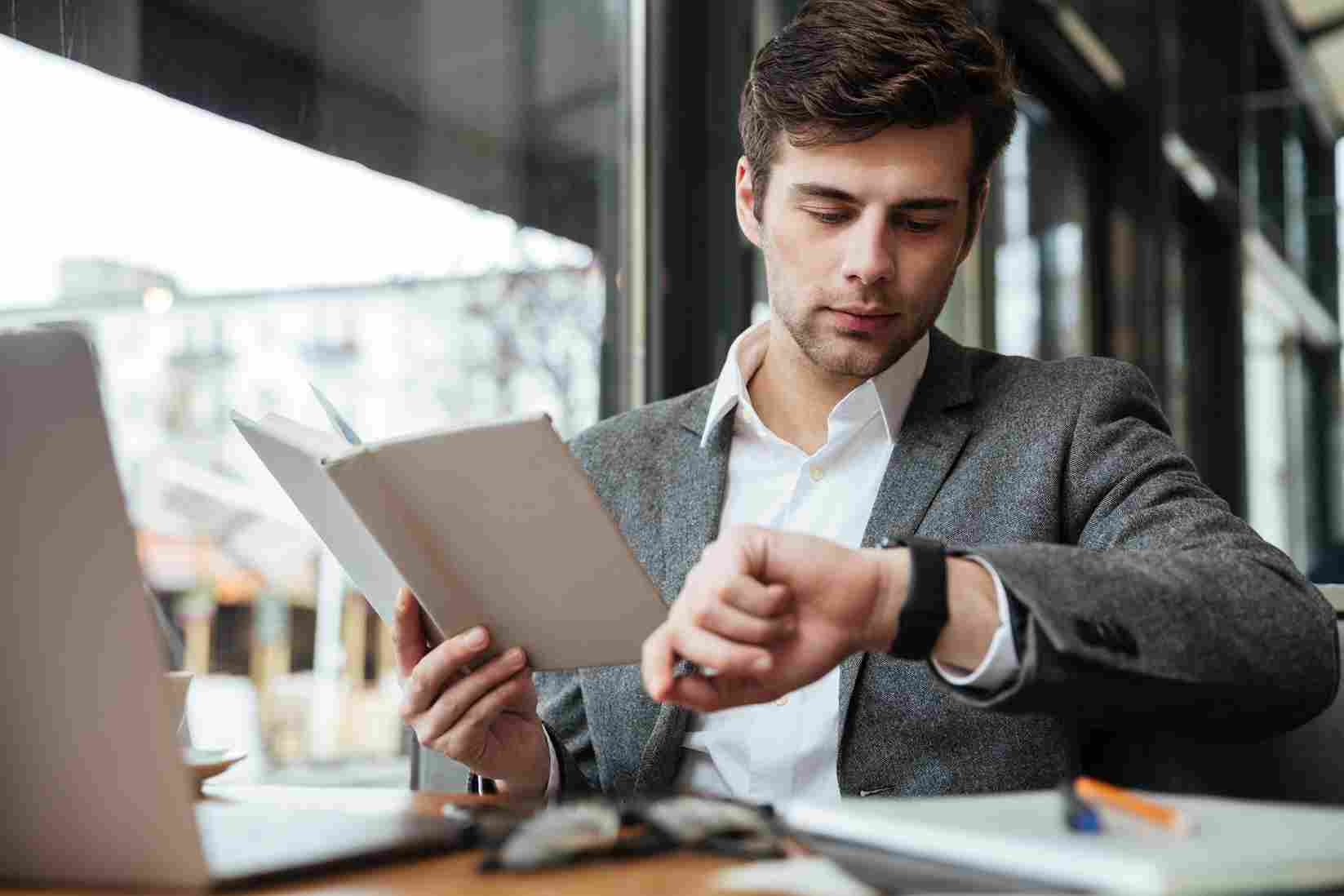Man looking at his watch while holding a document