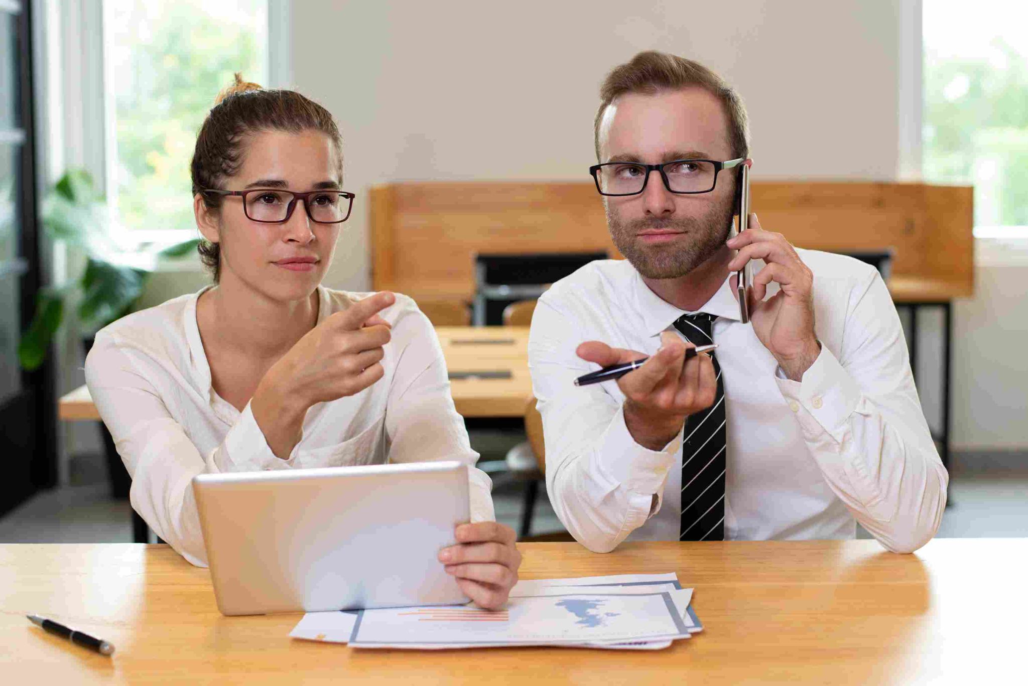 Man and woman looking confused or frustrated at a laptop, with the man on a phone call