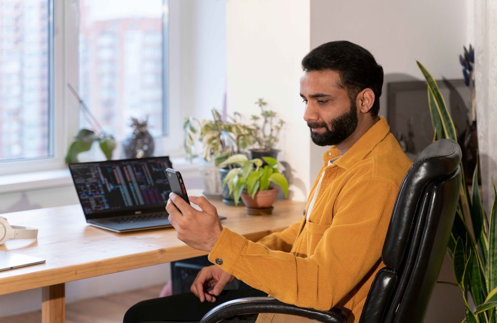 Man looking at phone while working on a laptop