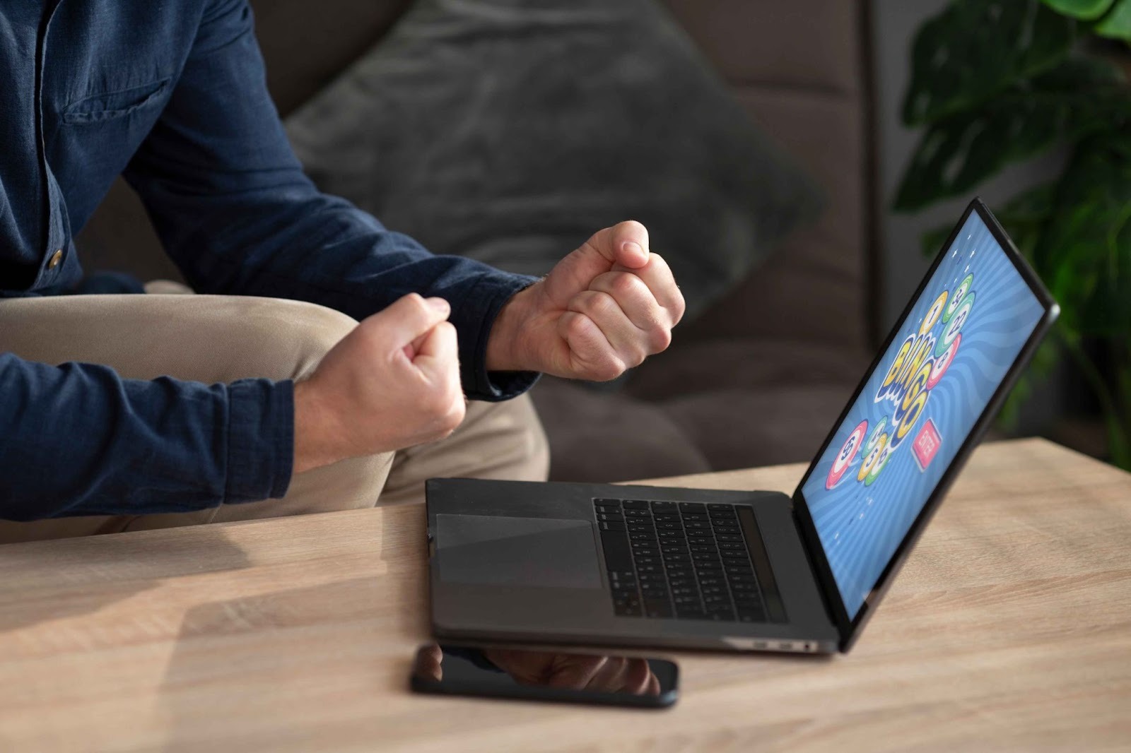 Person clenching fists in front of a laptop showing charts
