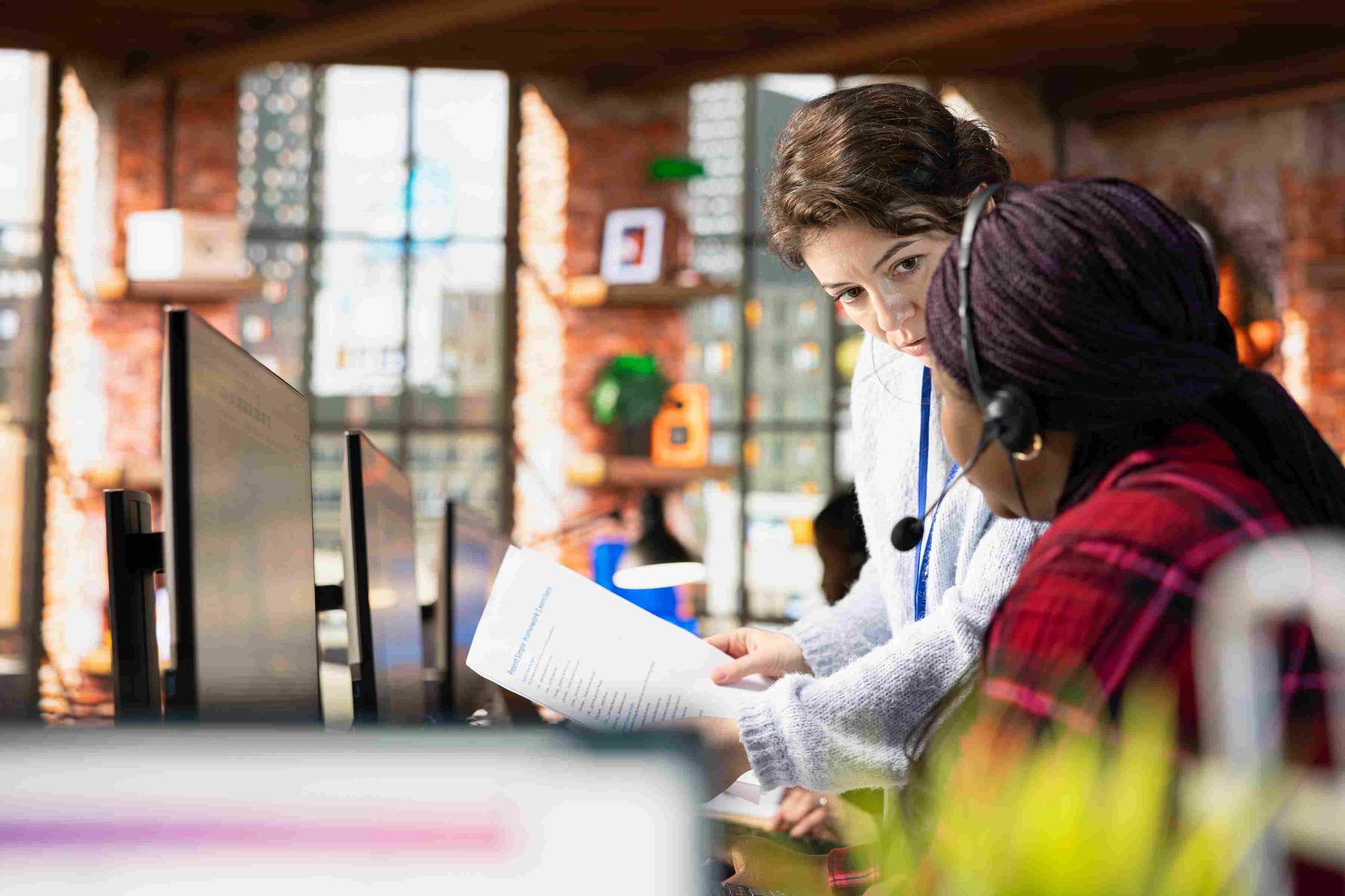 Two women looking at a computer screen in a library or office setting