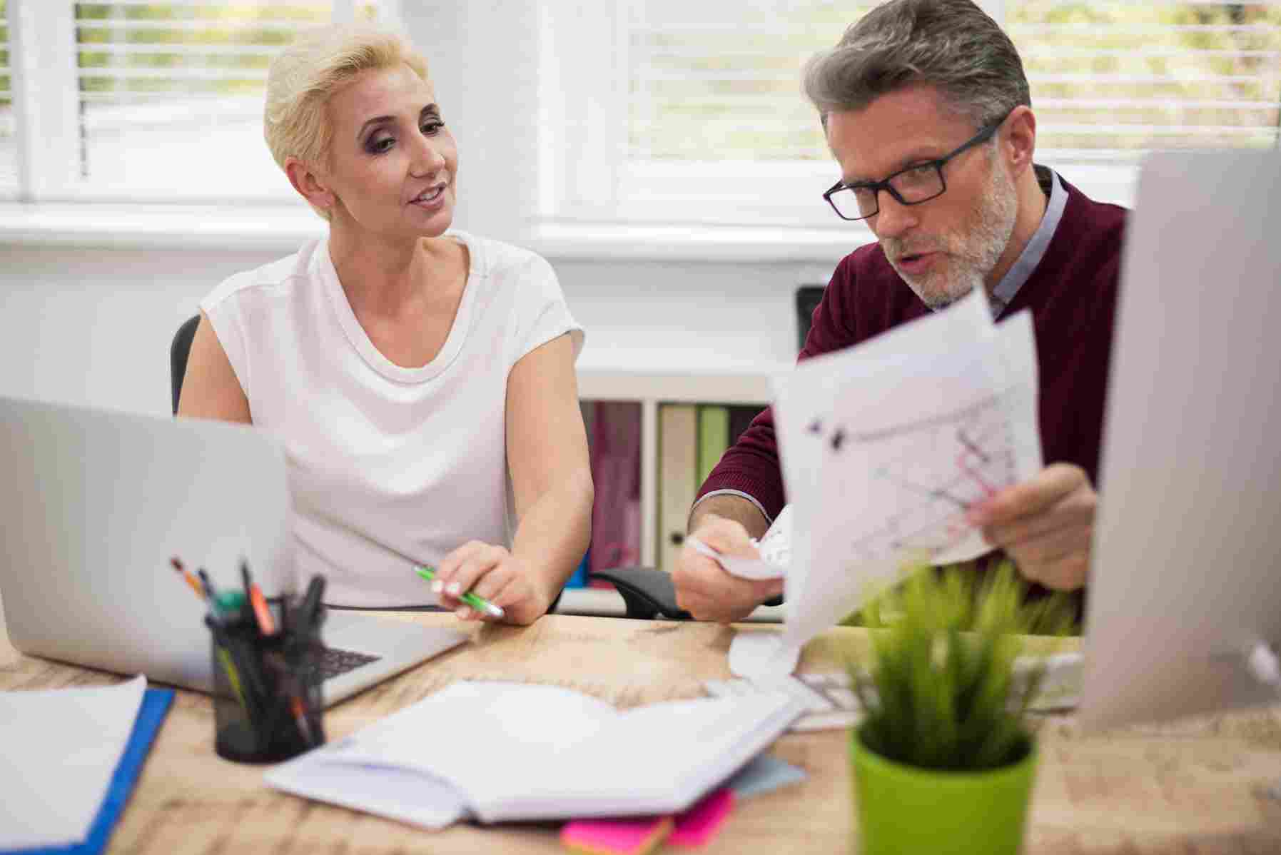 Colleagues discussing payroll schedule documentation