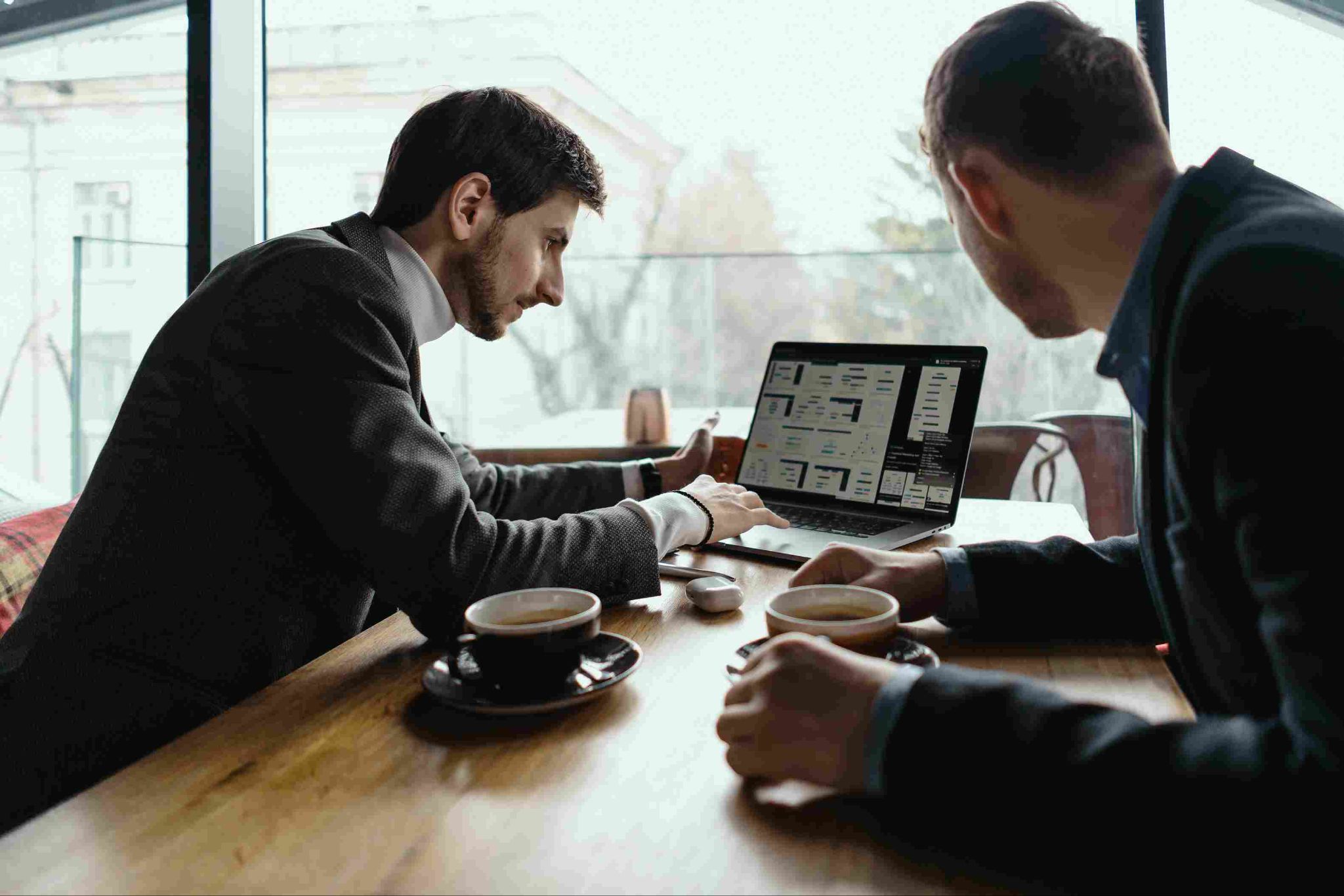 Two men looking at a laptop in a cafe or office setting